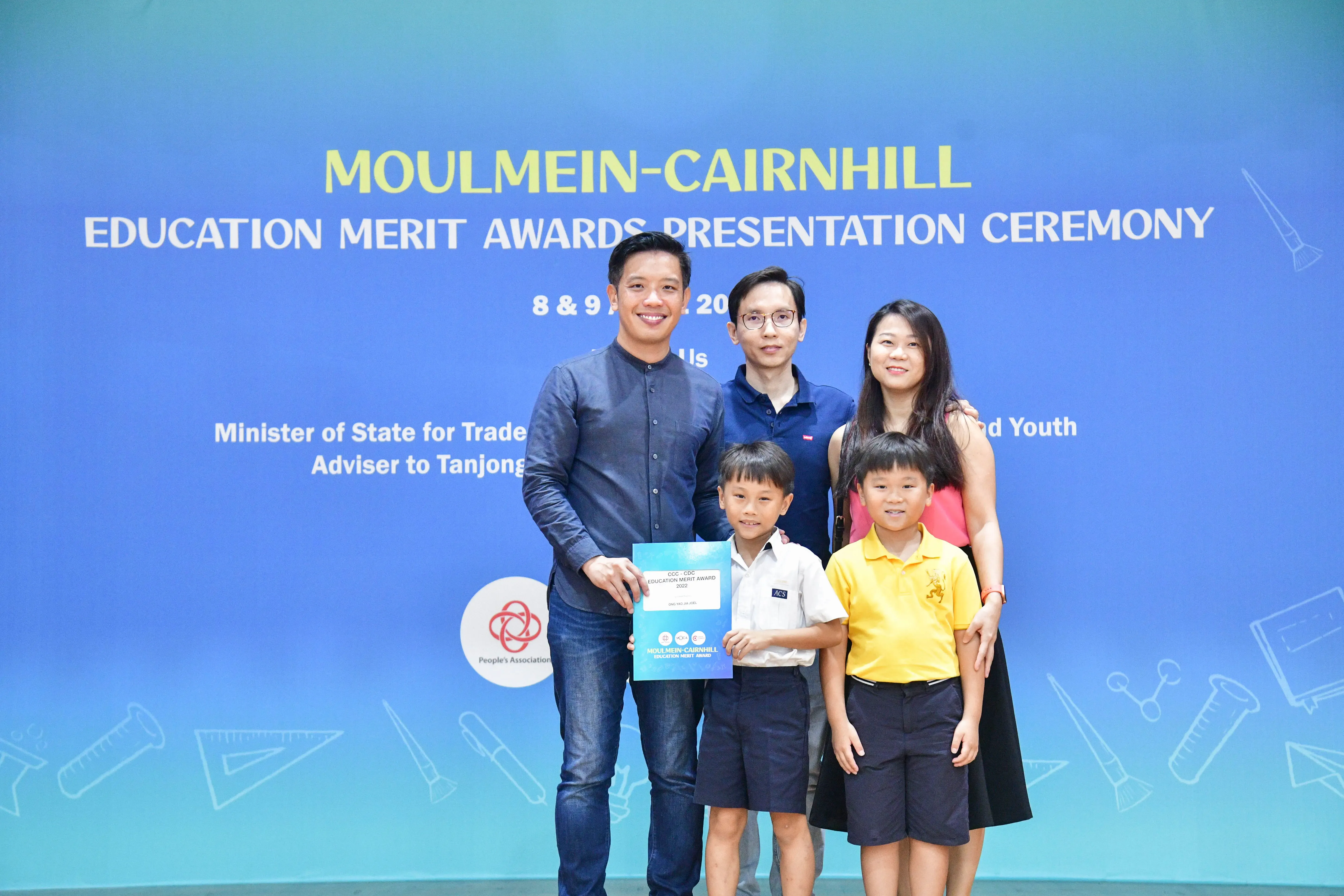 Three adults and two young boys pose at the Moulmein-Cairnhill Education Merit Awards Presentation Ceremony.