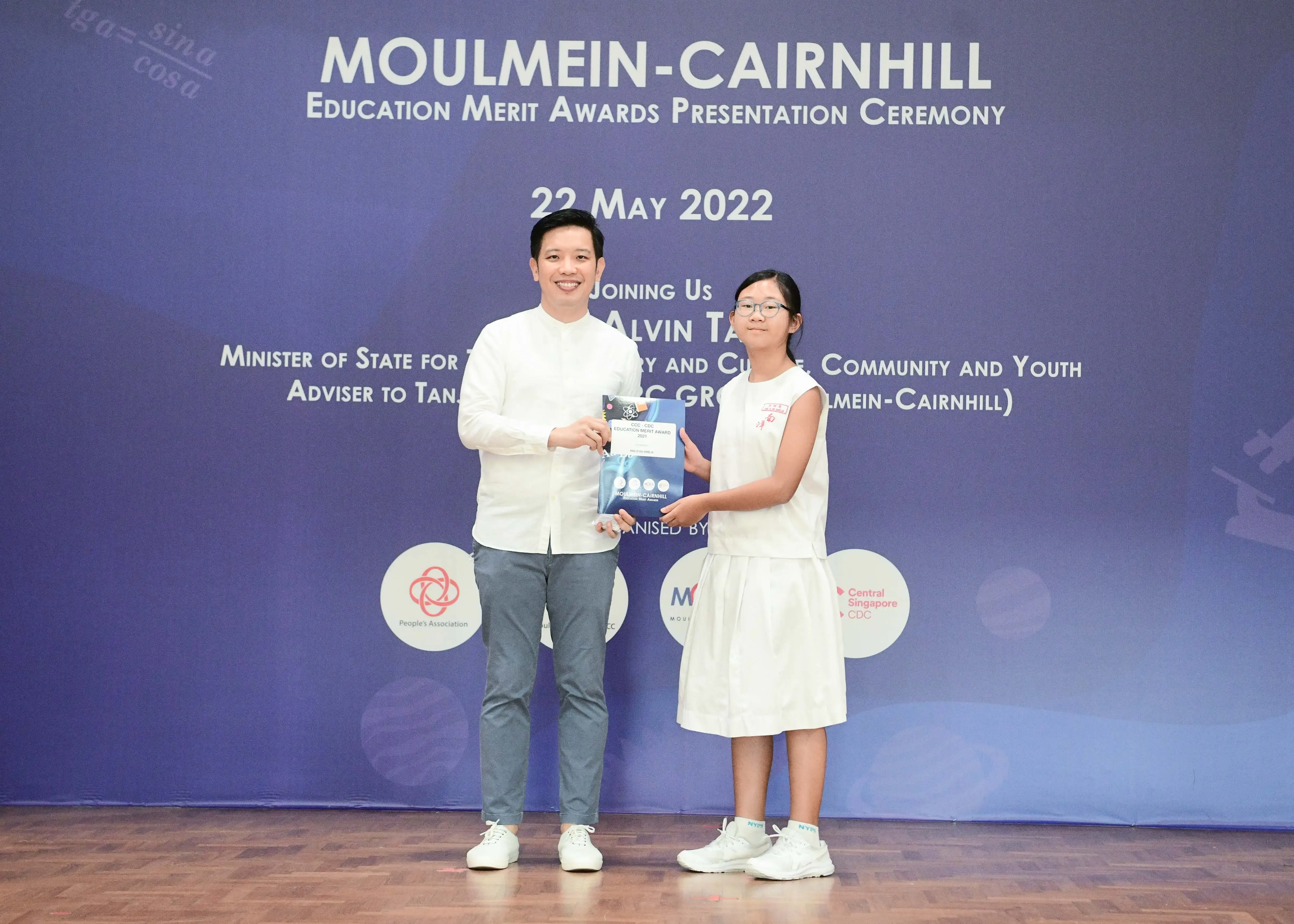 A man and a young girl hold a certificate together at the Moulmein-Cairnhill Education Merit Awards on 22 May 2022.