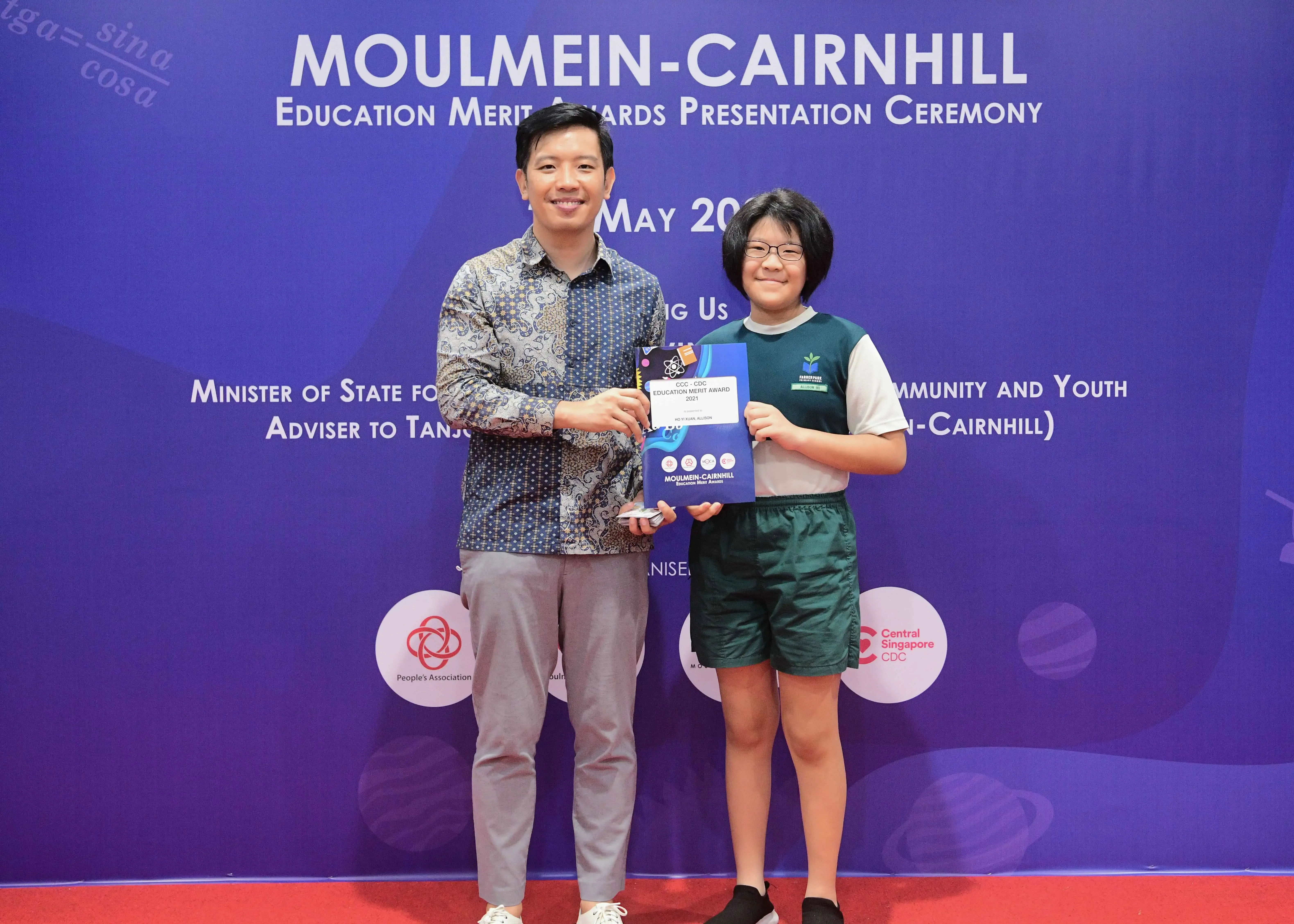A man and a young student pose together holding an award at the Moulmein-Cairnhill Education Merit Awards Ceremony.