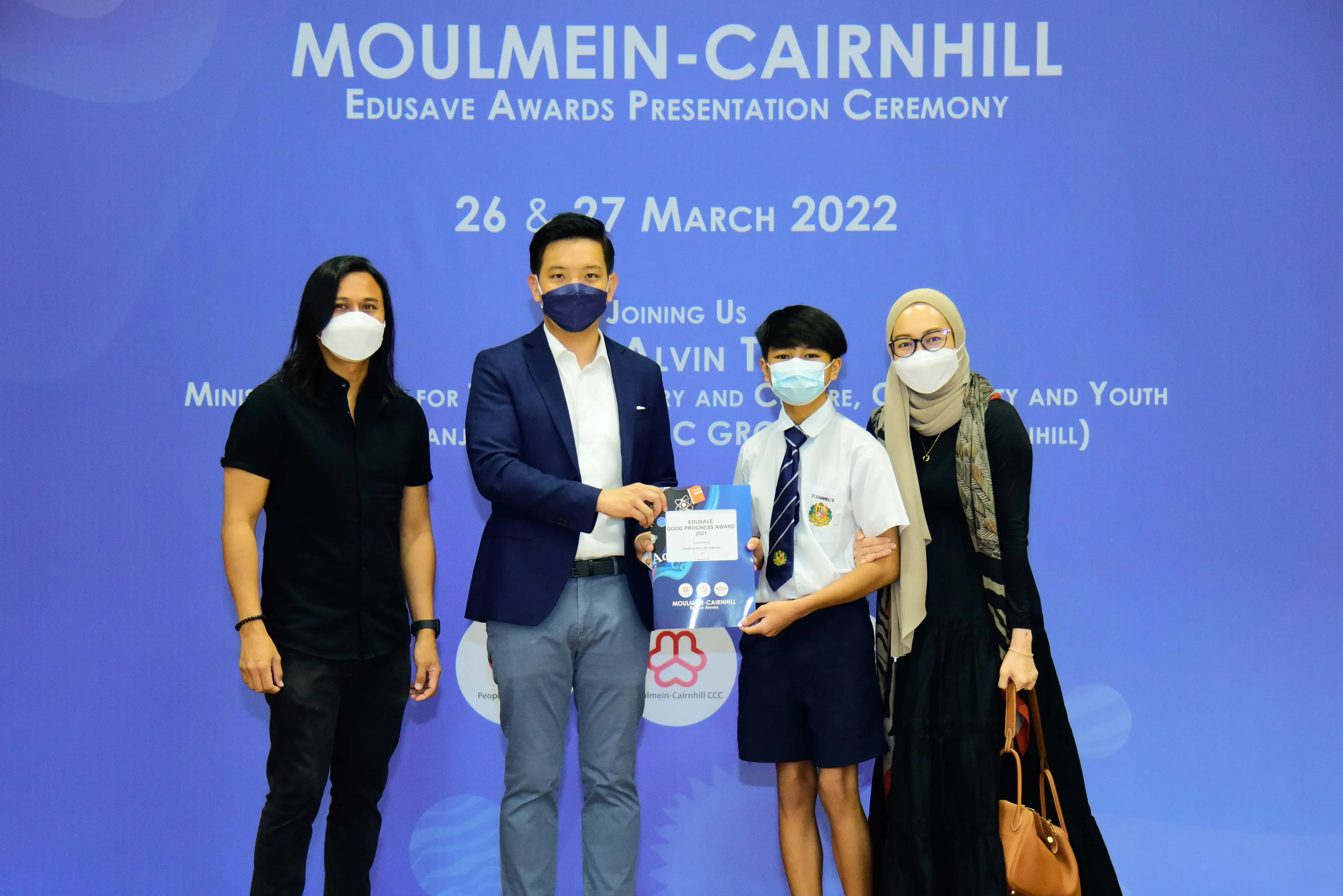 Four masked people pose at the Moulmein-Cairnhill Edusave Awards Presentation Ceremony on 26-27 March 2022.