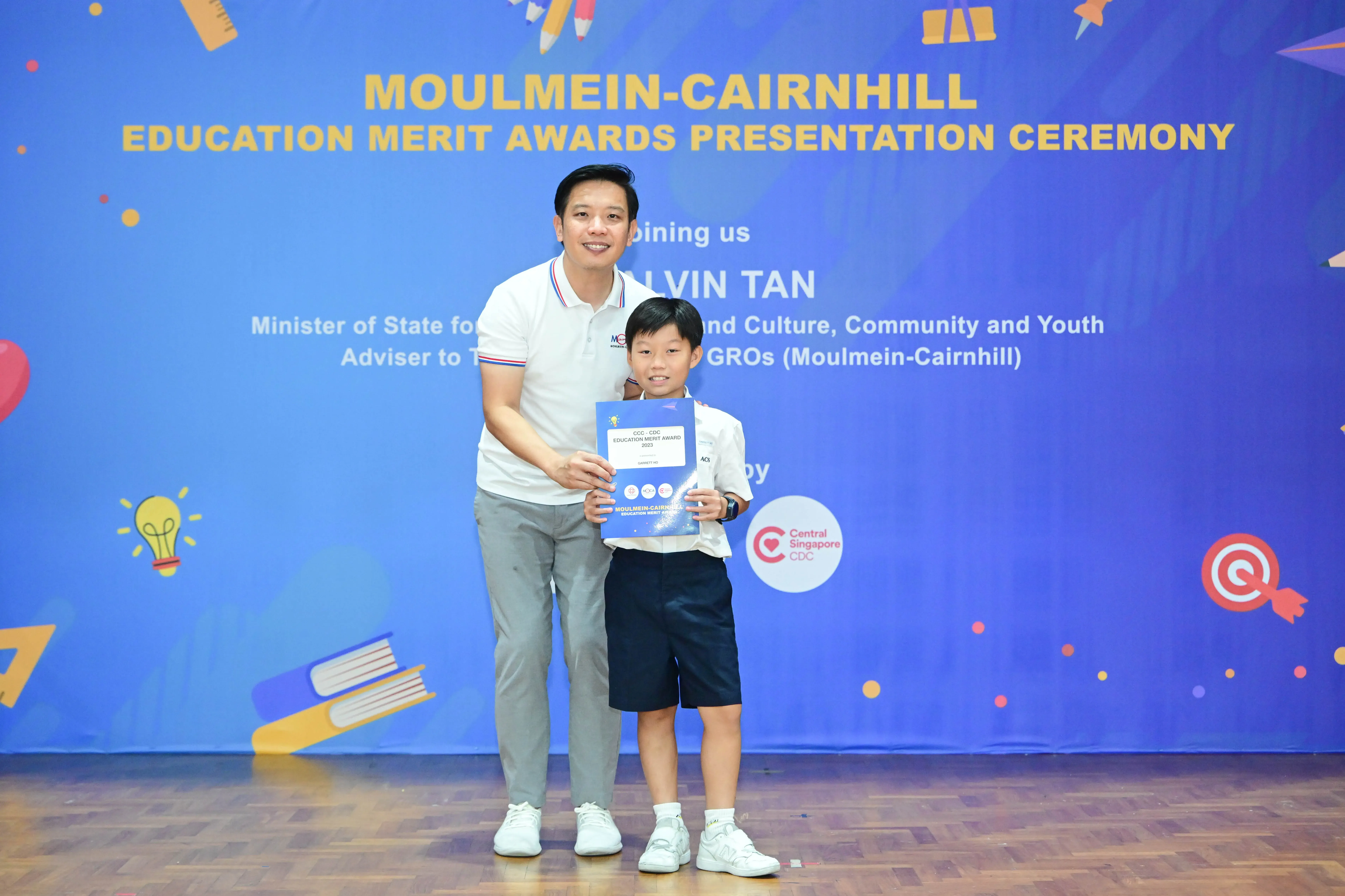 Man and young boy pose together holding a certificate at the Moulmein-Cairnhill Education Merit Awards Ceremony.