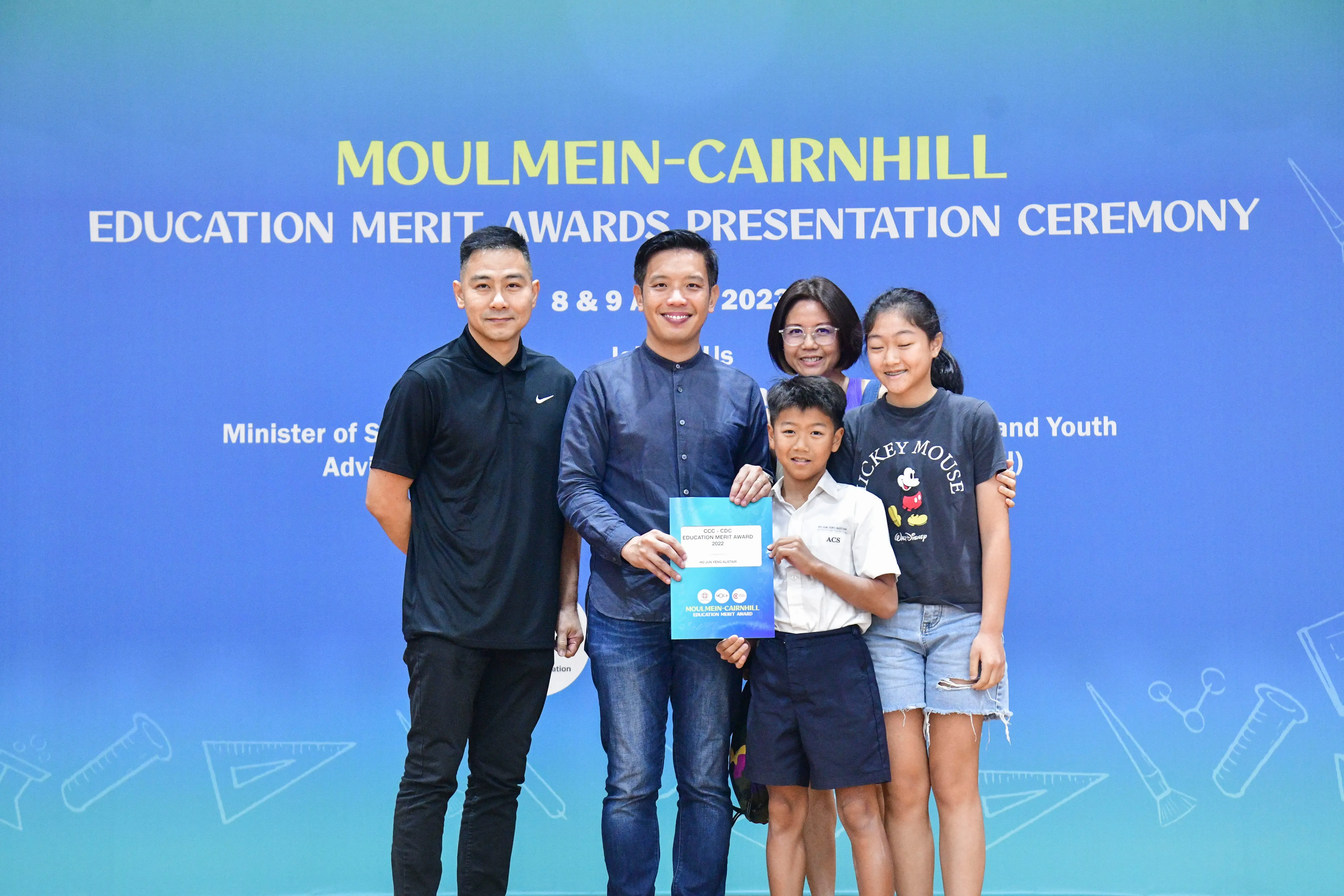 Five people pose holding an award certificate at the Moulmein-Cairnhill Education Merit Awards Presentation Ceremony.