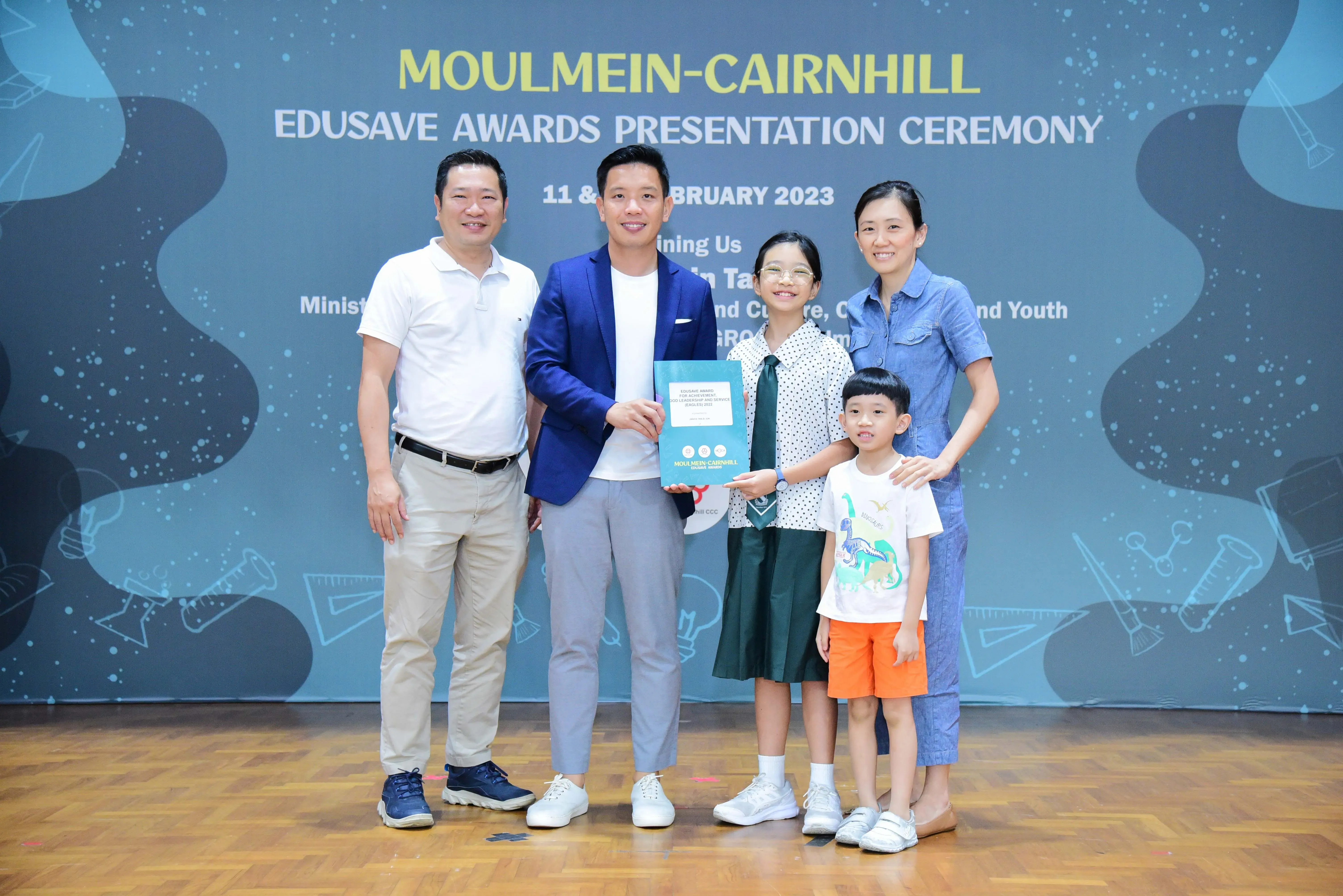 Five people pose at the Moulmein-Cairnhill Edusave Awards Presentation Ceremony, February 2023 backdrop.