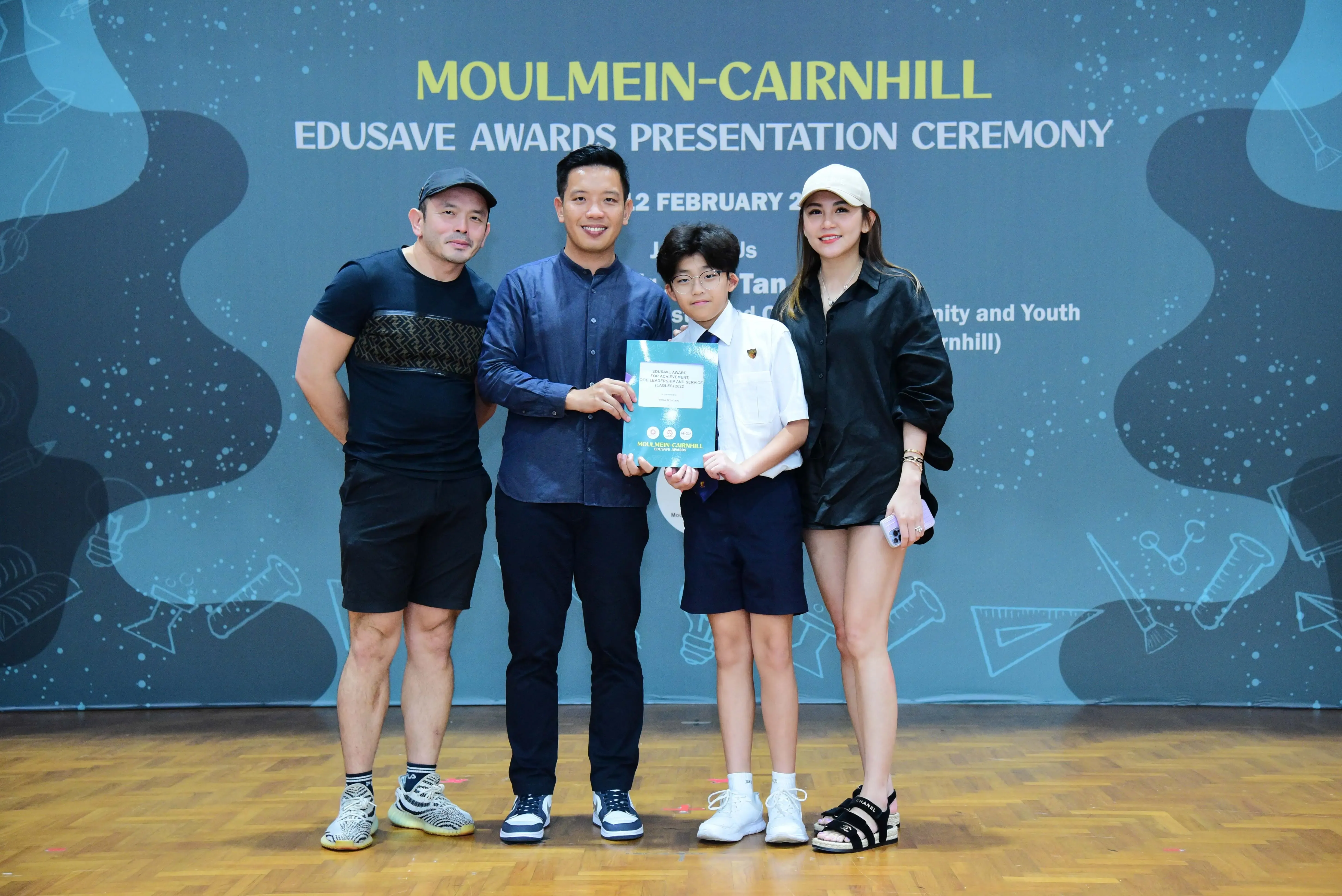 Four people pose with an award certificate at the Moulmein-Cairnhill Edusave Awards Presentation Ceremony.