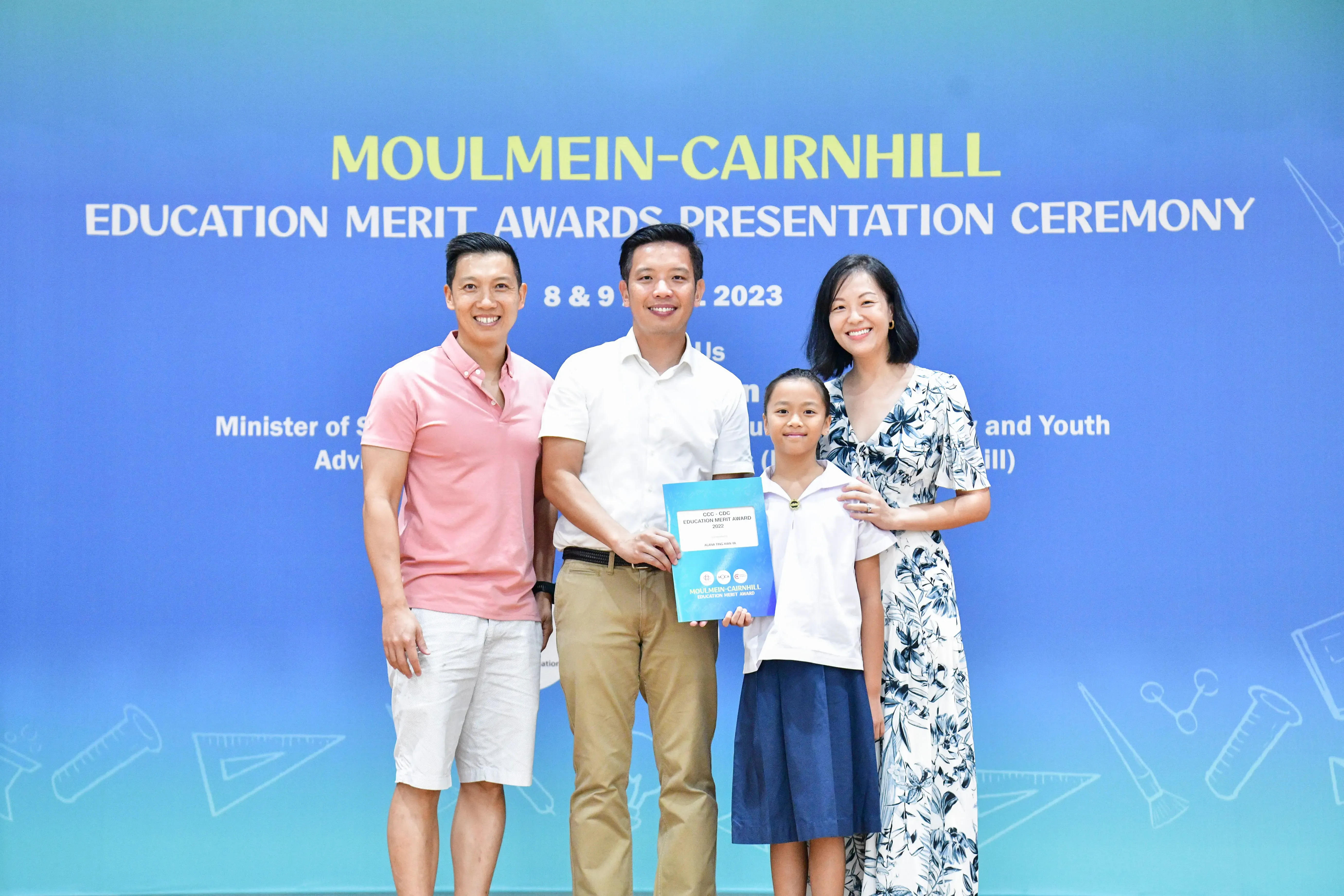 Three adults and a child pose with an award certificate at the Moulmein-Cairnhill Education Merit Awards 2023.