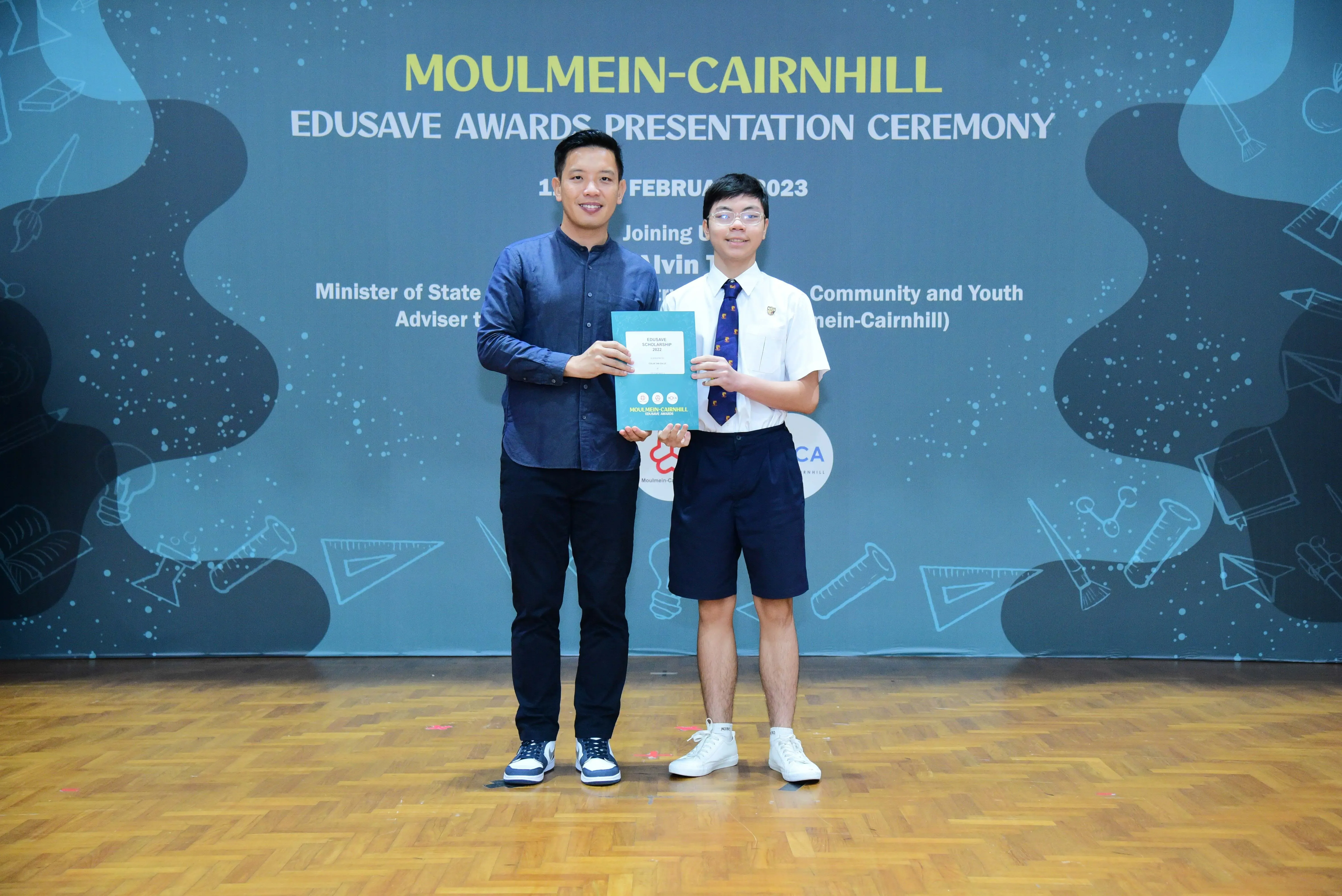 Two people hold an award certificate at the Moulmein-Cairnhill Edusave Awards Presentation Ceremony in February 2023.