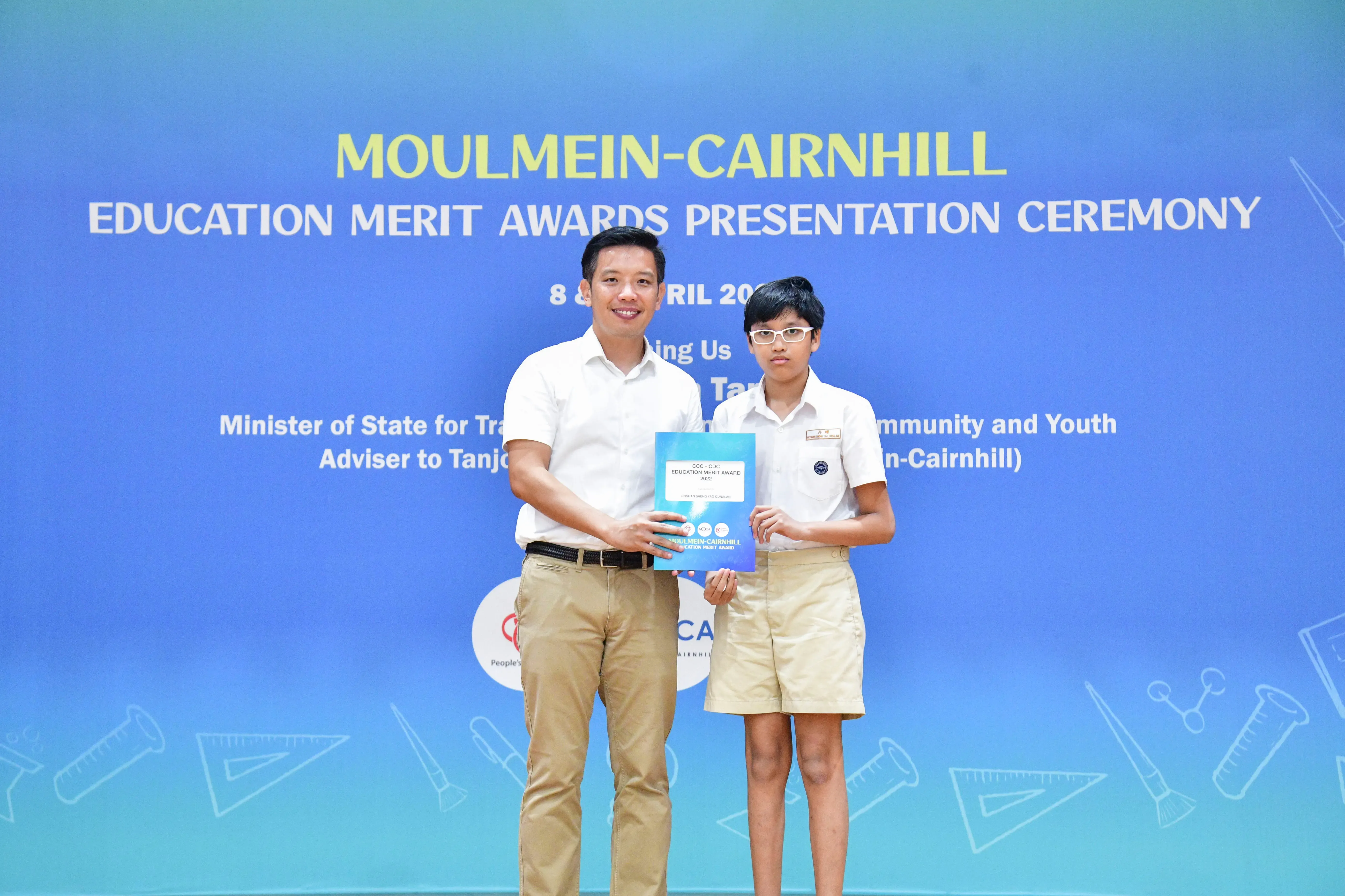 Adult and young student holding a certificate at the Moulmein-Cairnhill Education Merit Awards Presentation Ceremony.