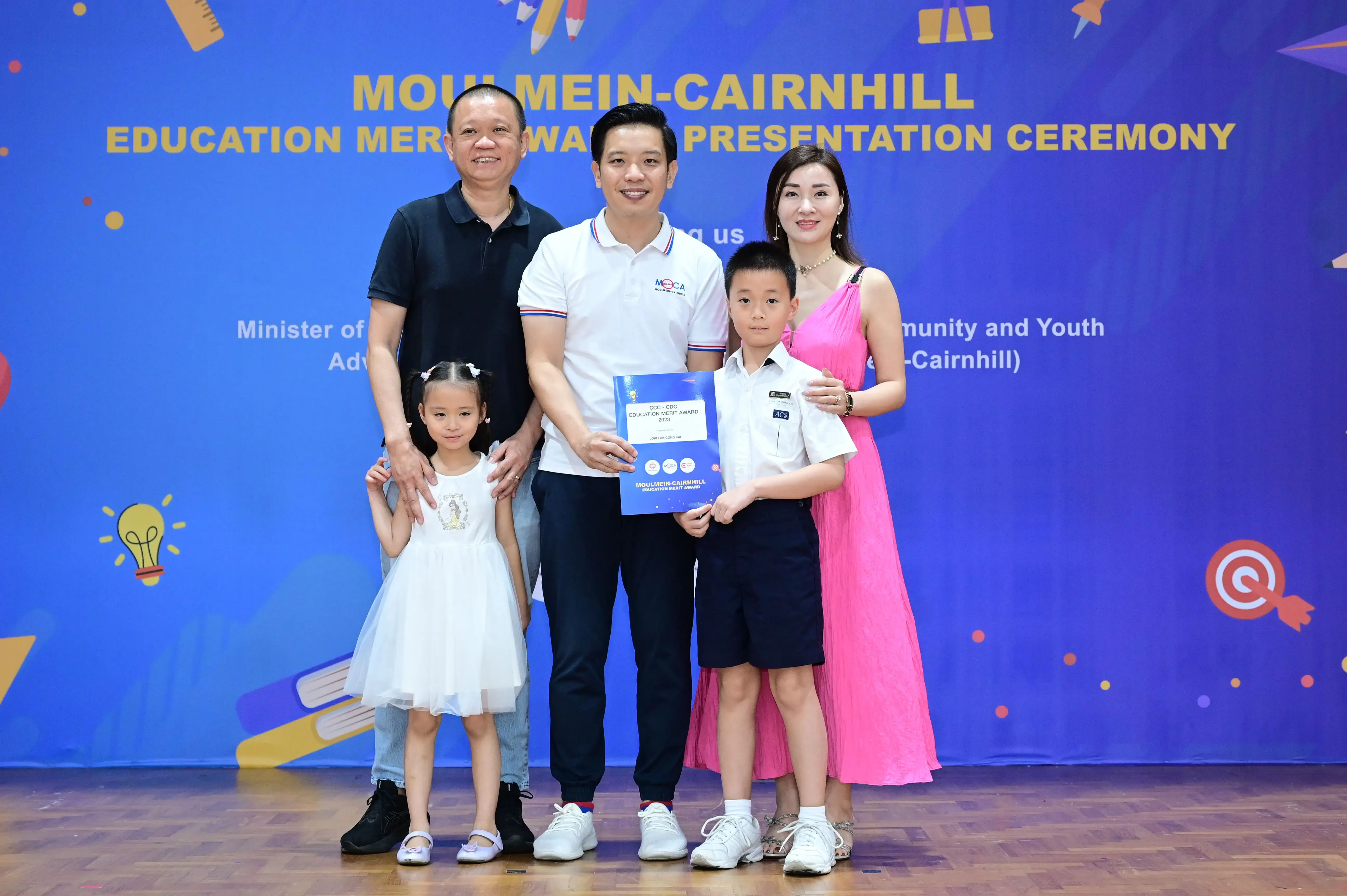 Five people pose with an award certificate at the Moulmein-Cairnhill Education Merit Award Presentation Ceremony.