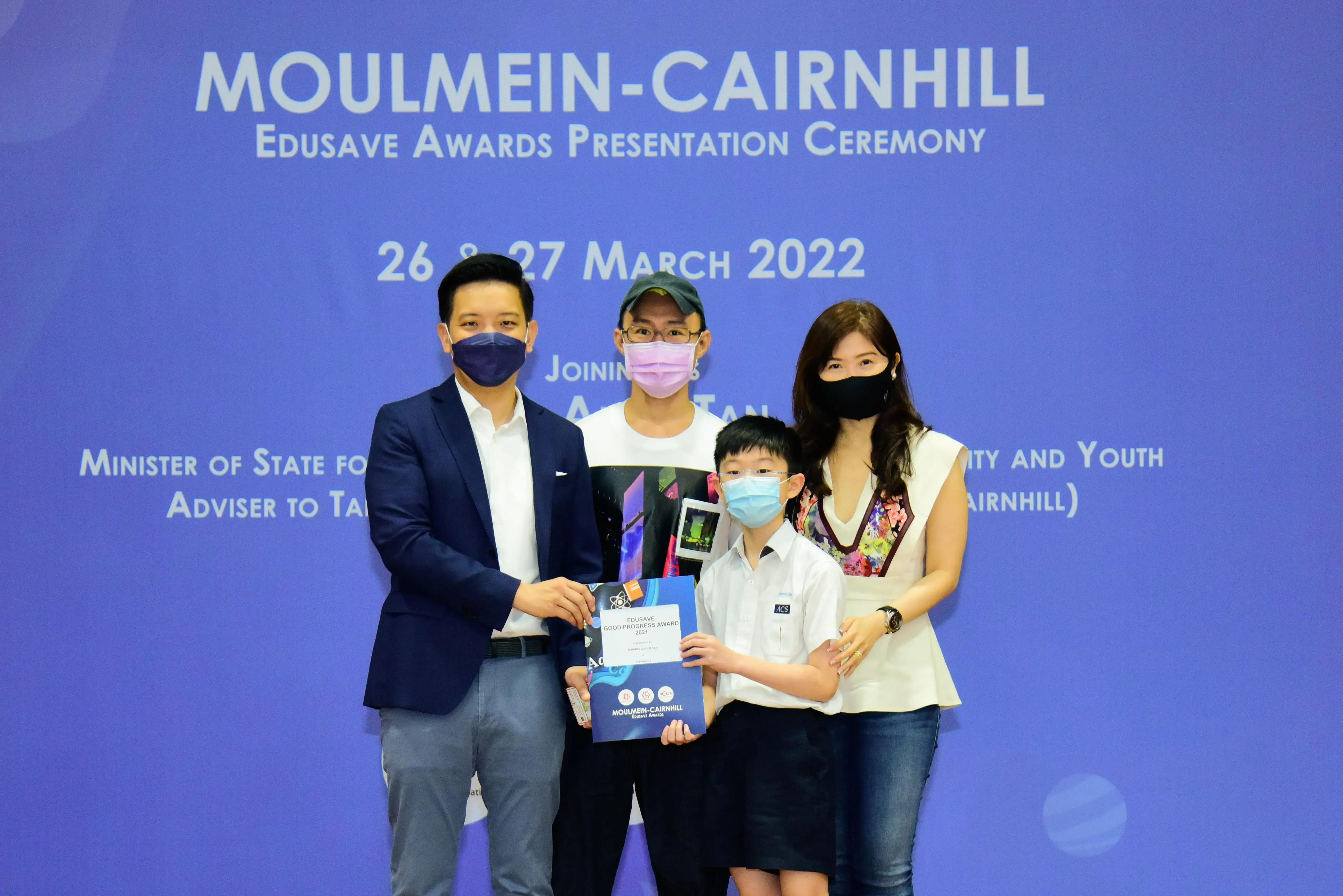 Four masked people pose at the Moulmein-Cairnhill Edusave Awards Presentation Ceremony on 26-27 March 2022.