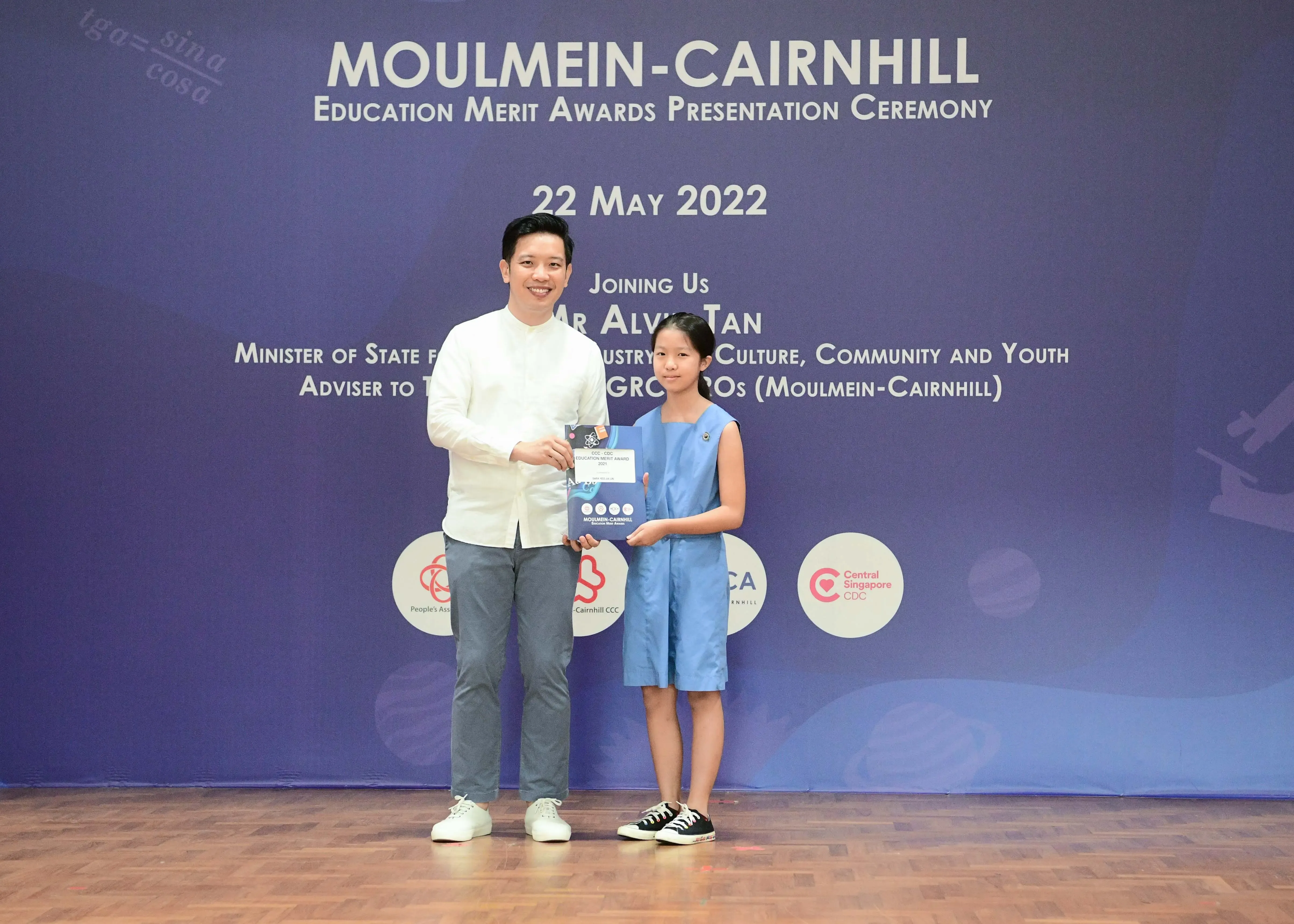 A man and a young girl hold an award together at the Moulmein-Cairnhill Education Merit Awards Ceremony on 22 May 2022.