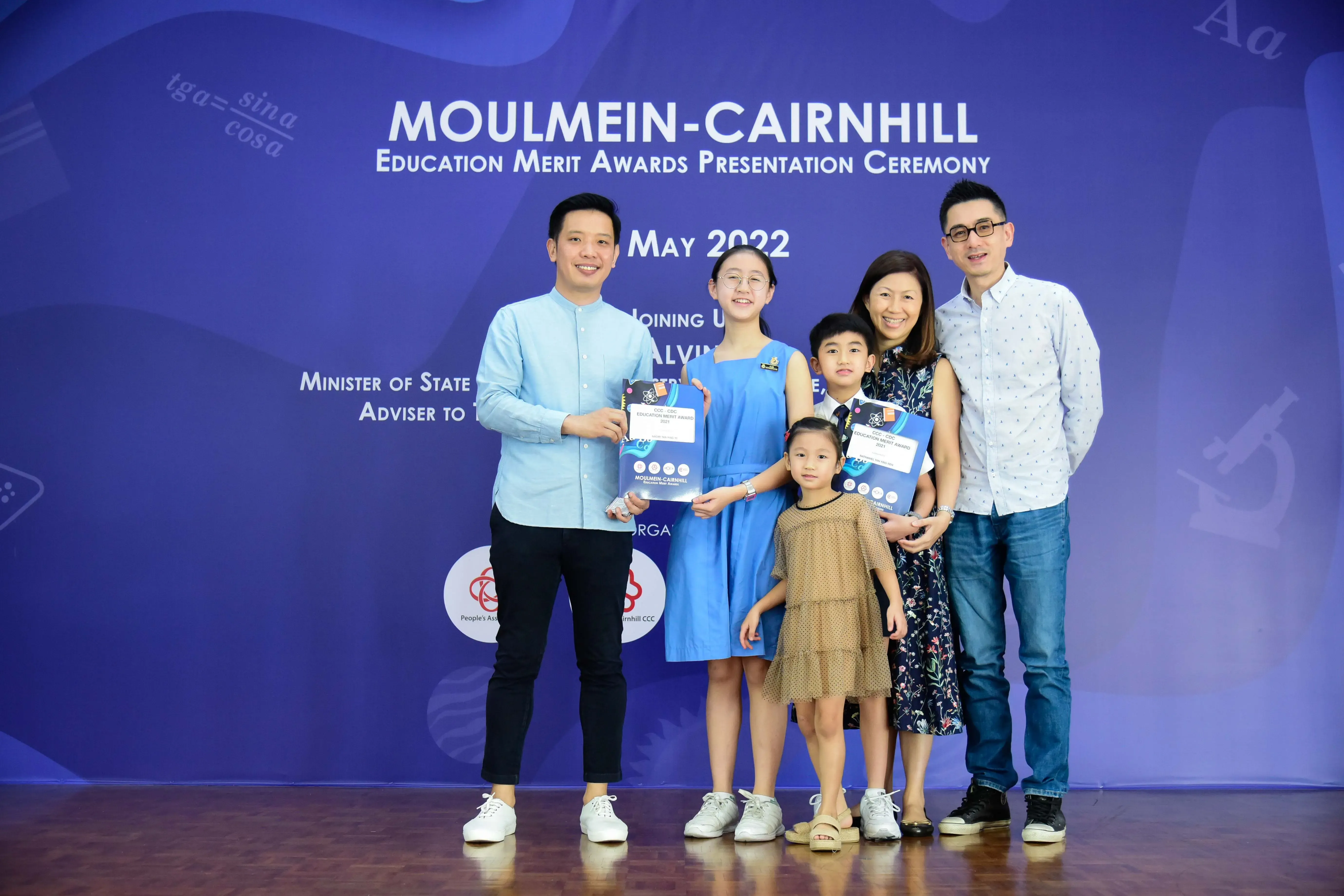 Six people pose holding award folders at the Moulmein-Cairnhill Education Merit Awards Ceremony, May 2022.