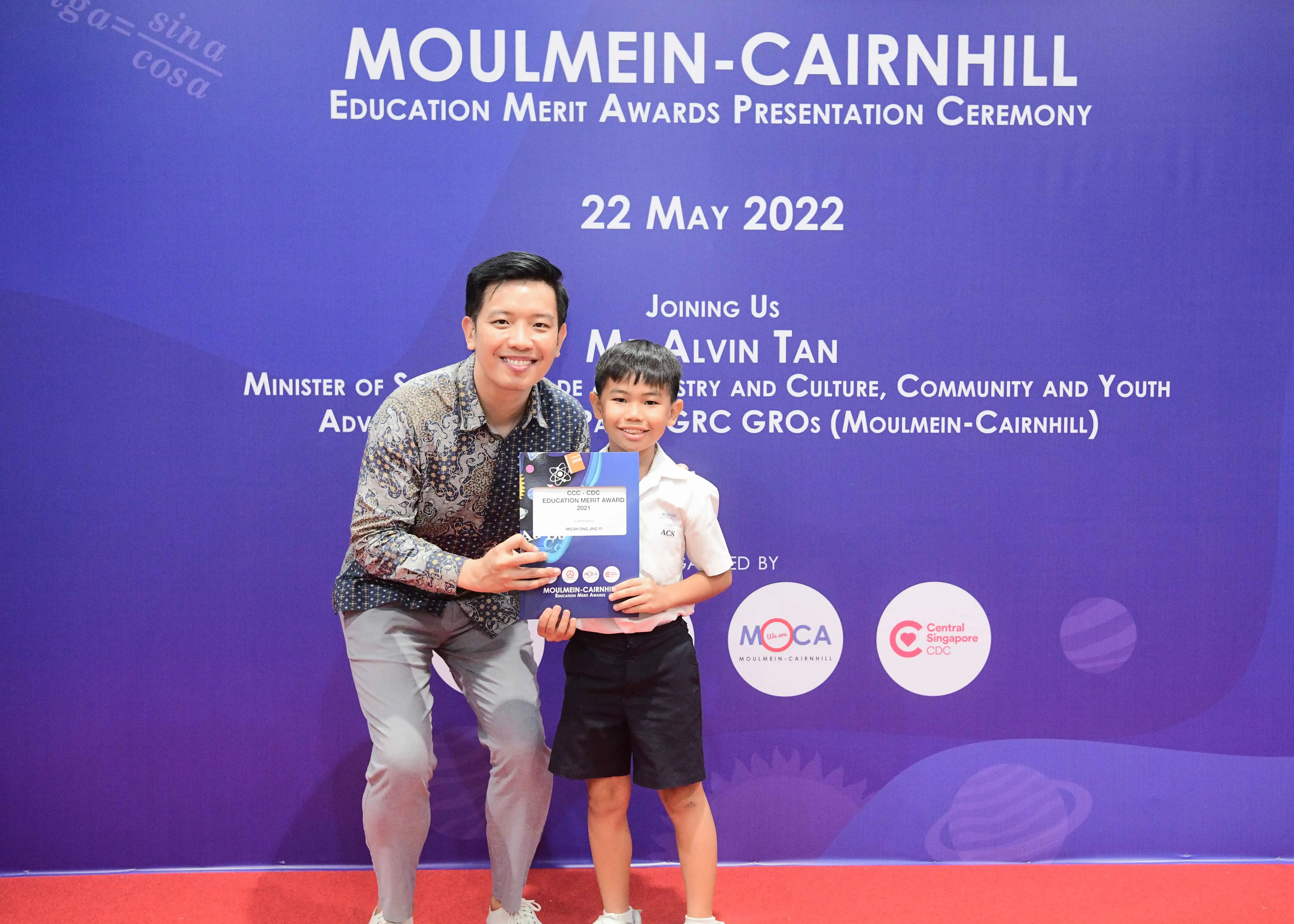 A man and a young boy hold an award certificate at the Moulmein-Cairnhill Education Merit Awards on 22 May 2022.