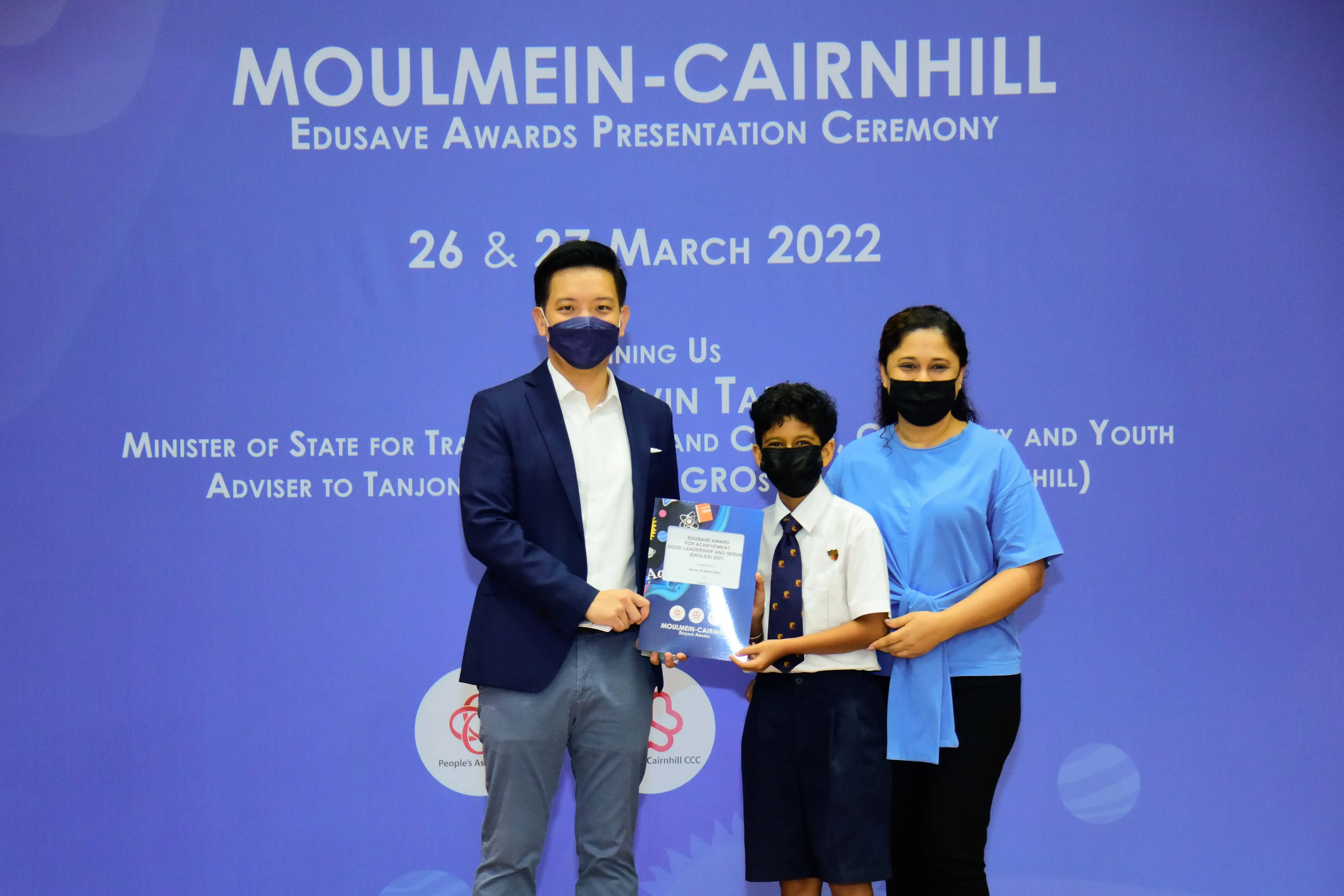 Three masked people hold an award certificate at the Moulmein-Cairnhill Edusave Awards Ceremony, March 2022.