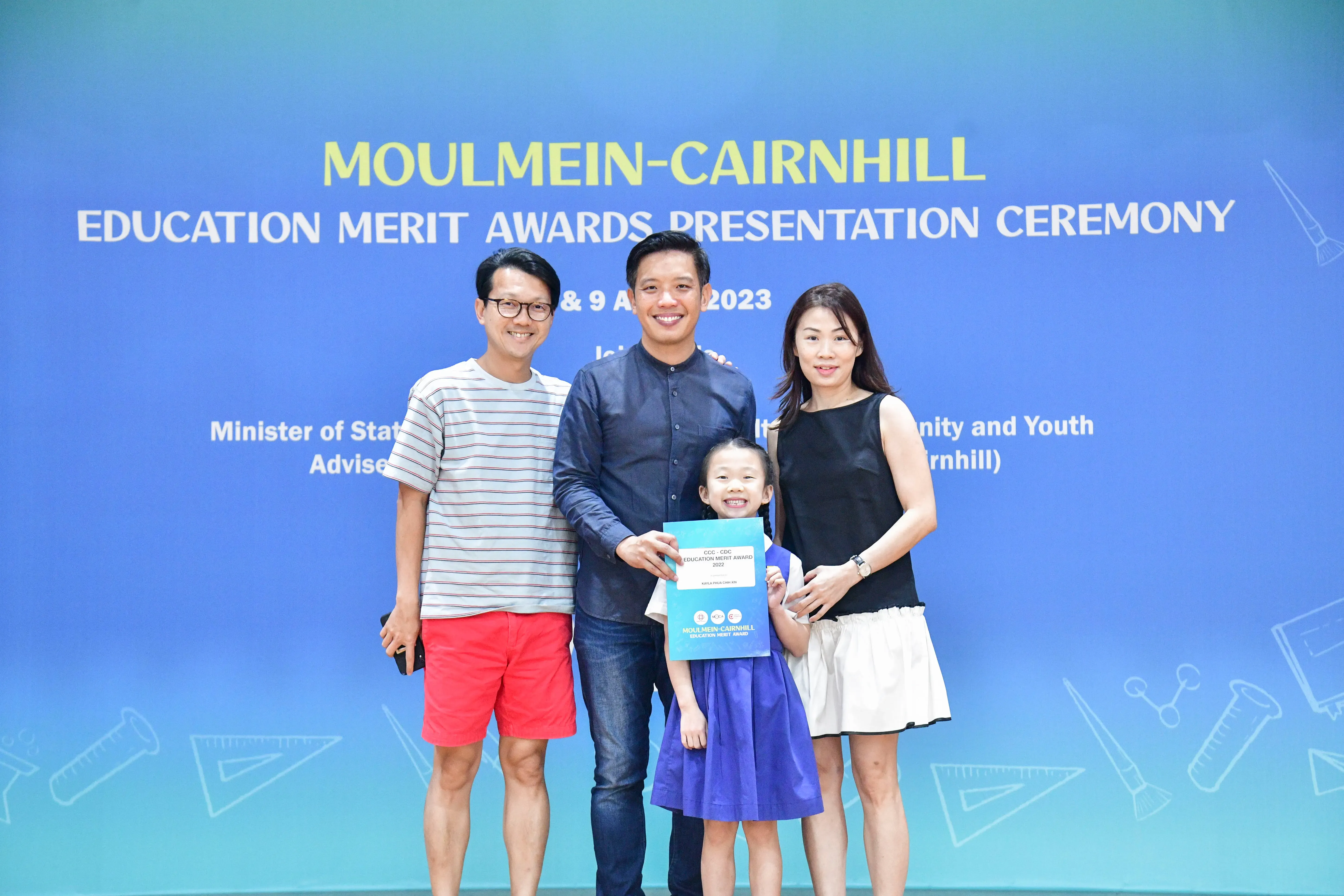 Three adults and a young girl pose with an award certificate at the Moulmein-Cairnhill Education Merit Awards 2023.