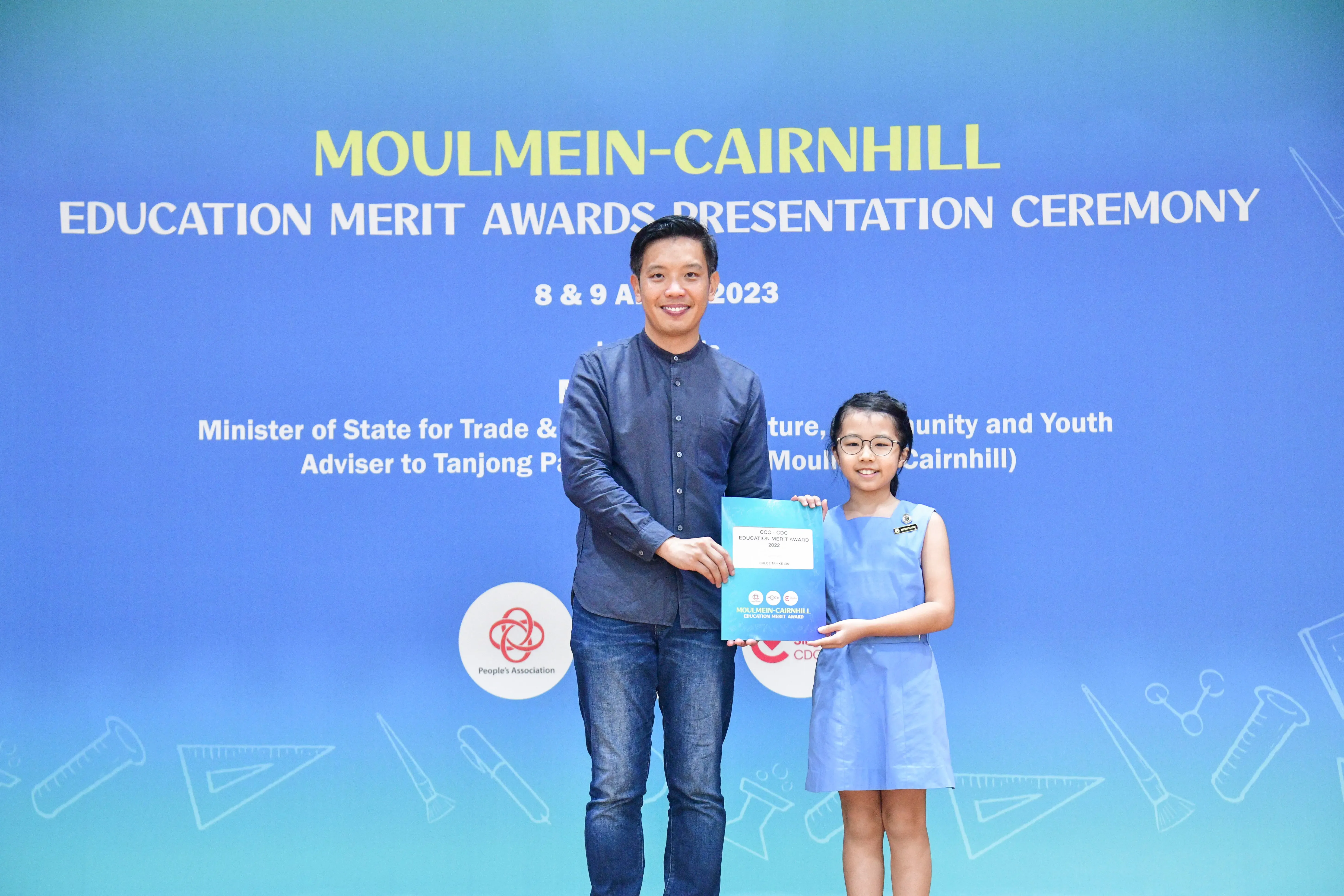 A man and a young girl hold a certificate at the Moulmein-Cairnhill Education Merit Awards Ceremony 2023.