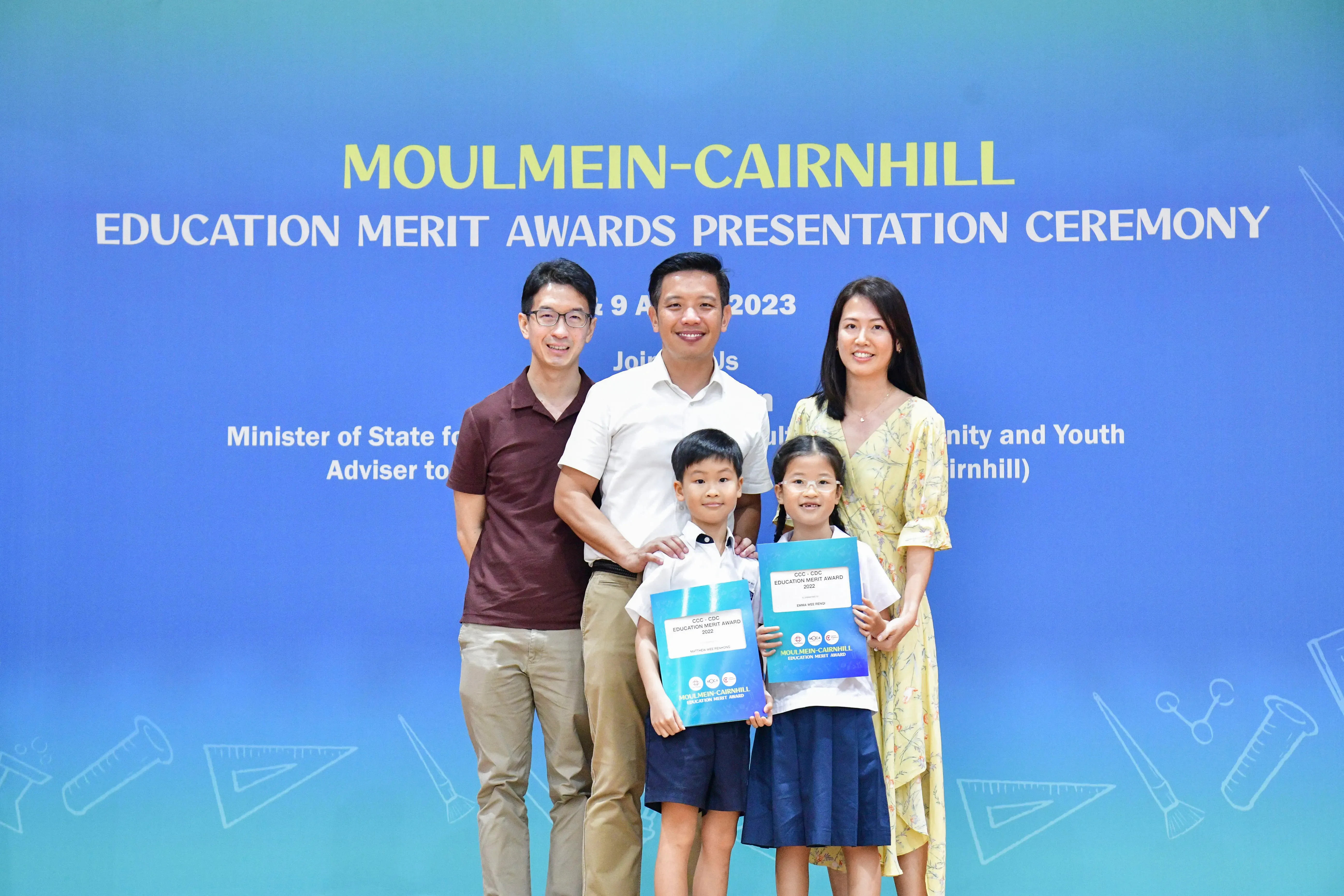 Three adults and two children pose with award certificates at the Moulmein-Cairnhill Education Merit Awards 2023.
