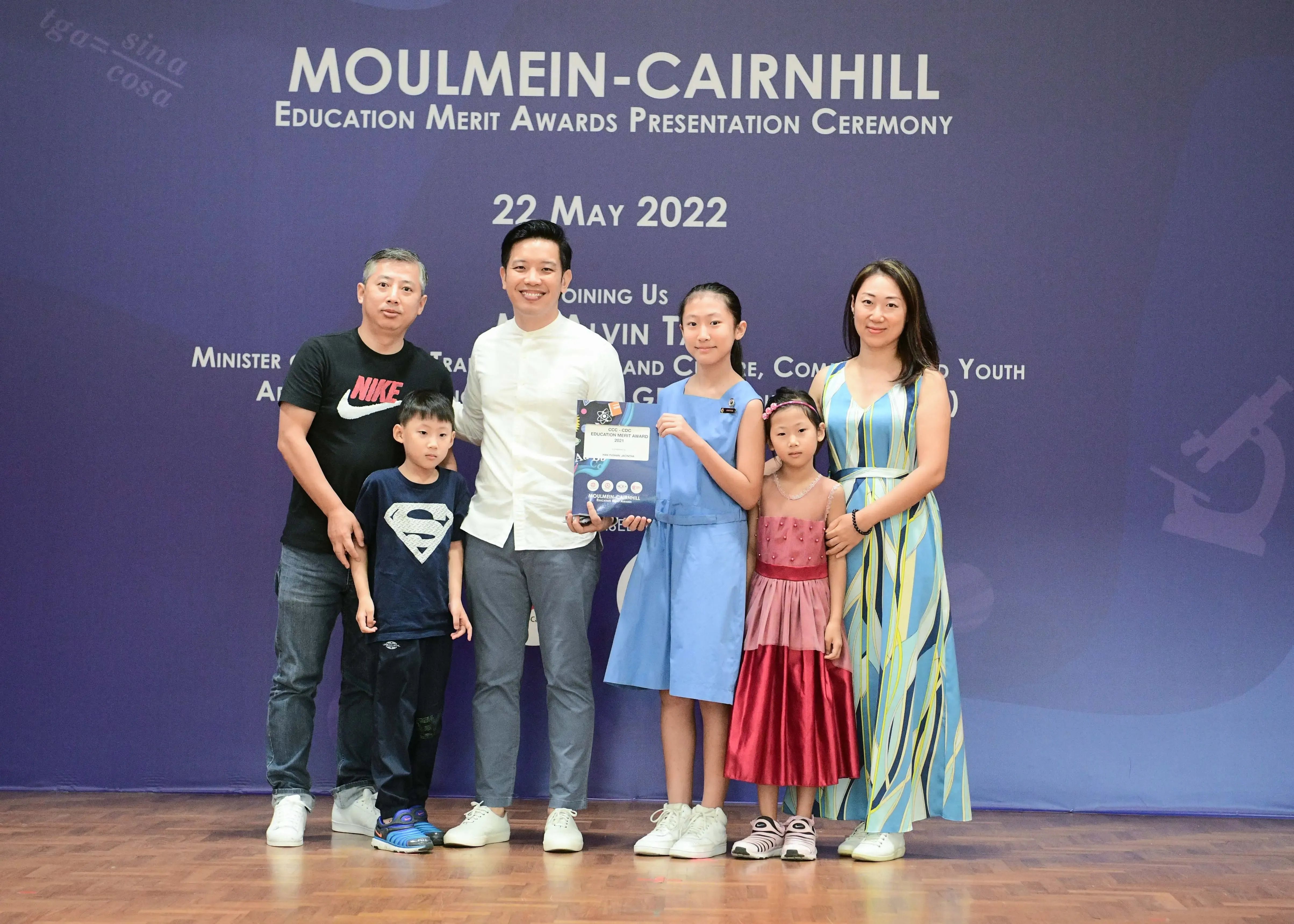 A family of five poses with an official holding an award certificate at the Moulmein-Cairnhill Education Merit Awards on 22 May 2022.