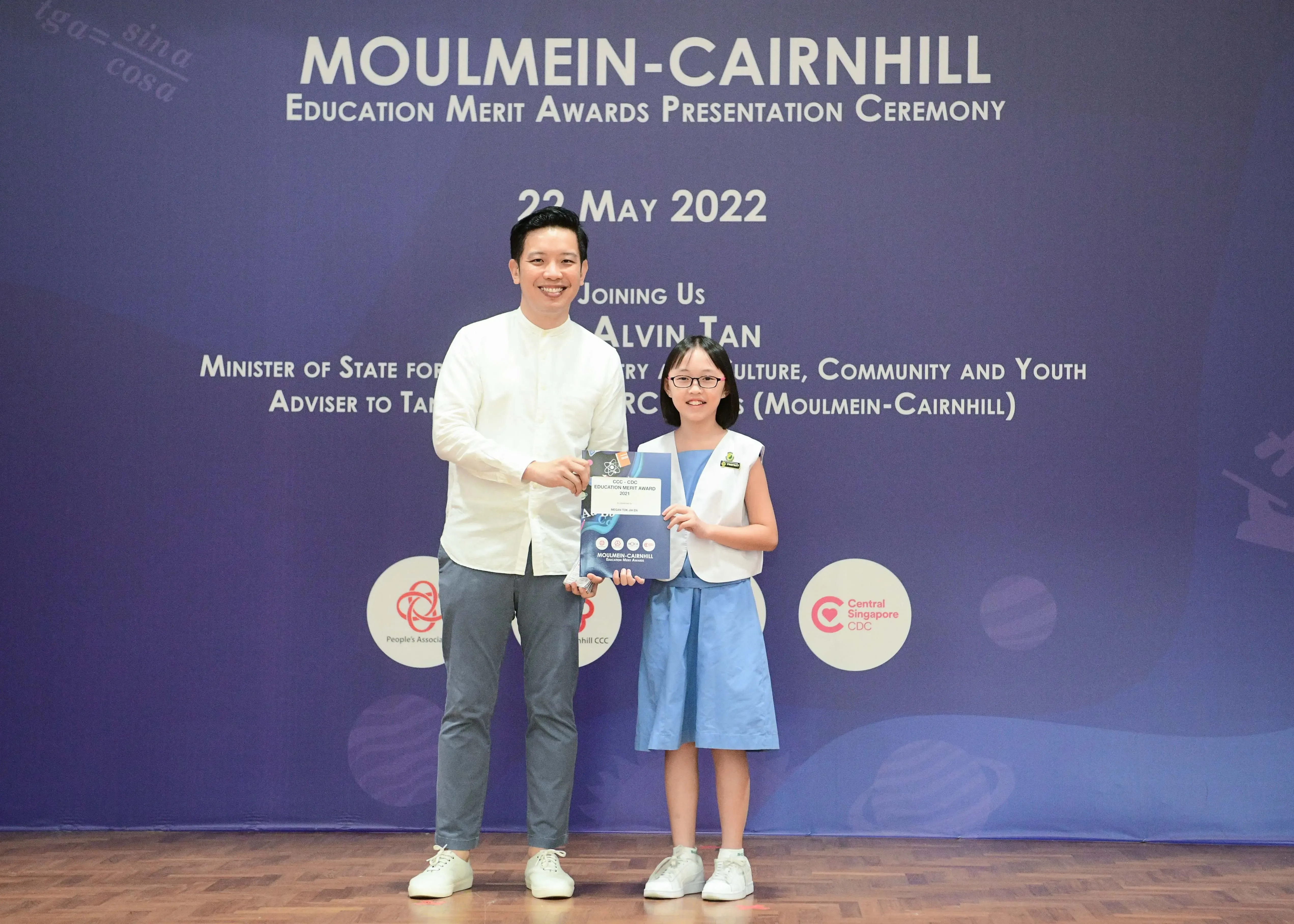 A man and a young girl pose together holding an award at the Moulmein-Cairnhill Education Merit Awards ceremony on 22 May 2022.