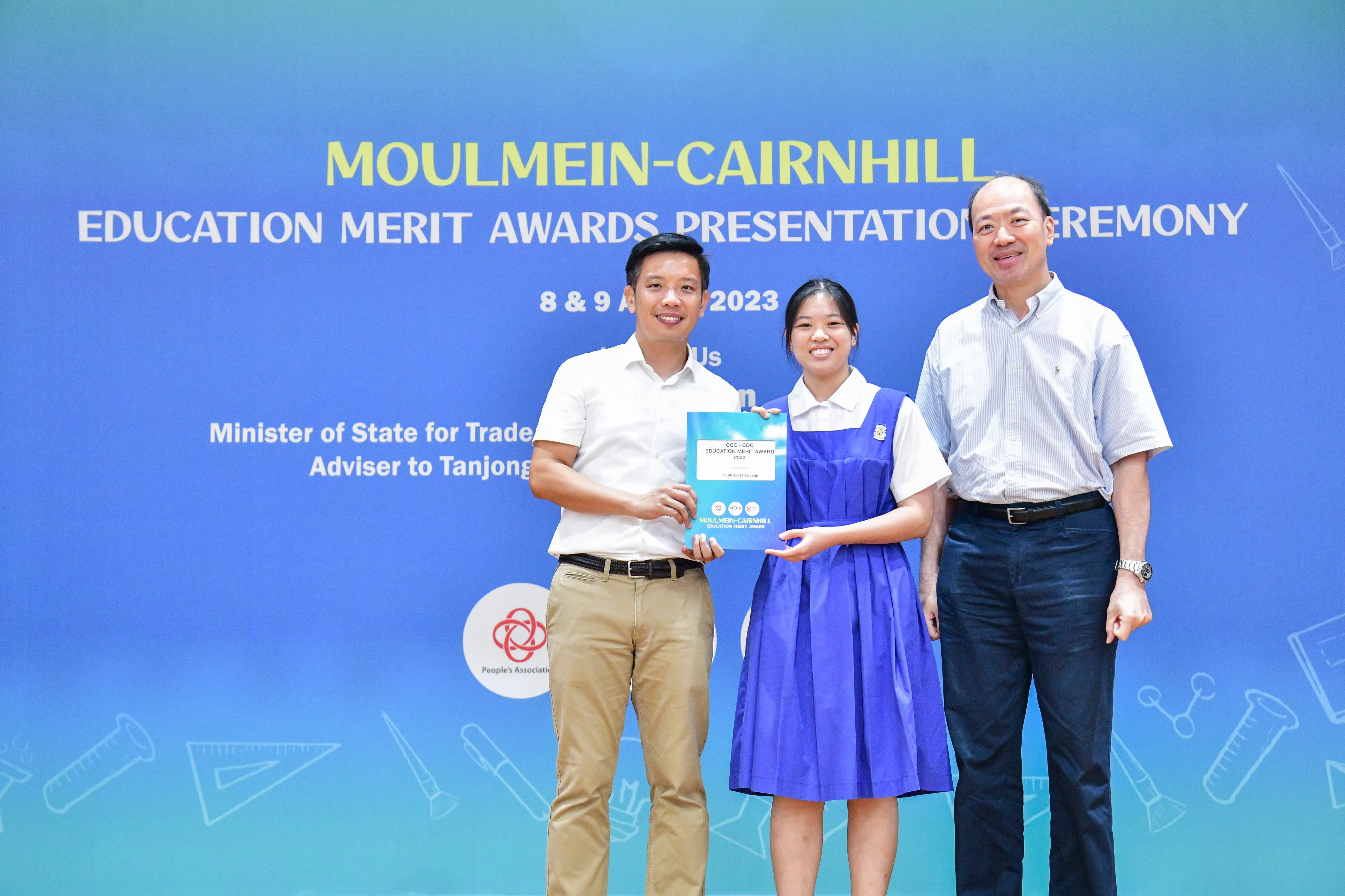 Three people pose holding an award at the Moulmein-Cairnhill Education Merit Awards Presentation Ceremony 2023.
