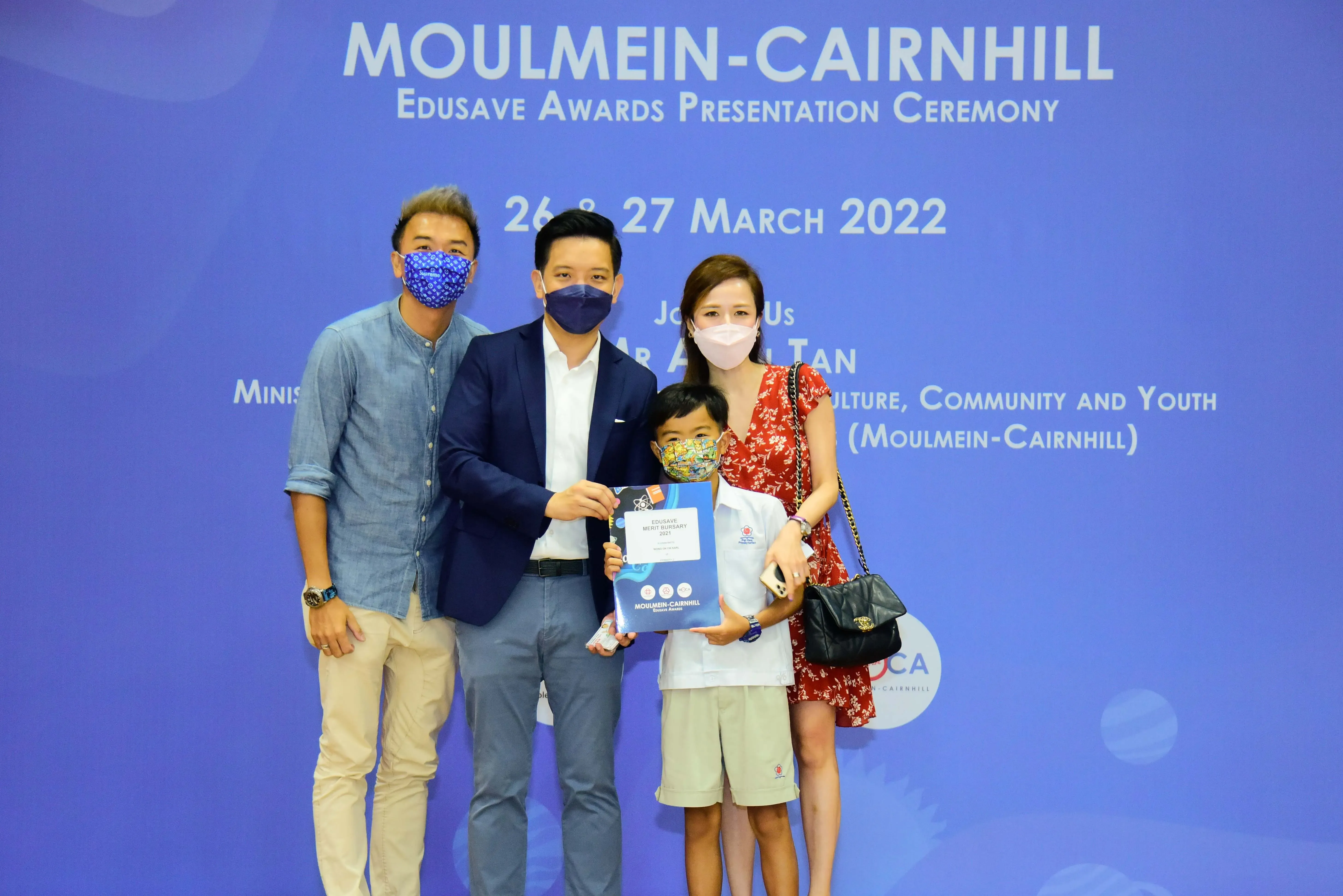Four masked people pose at the Moulmein-Cairnhill Edusave Awards Presentation Ceremony on 26-27 March 2022.
