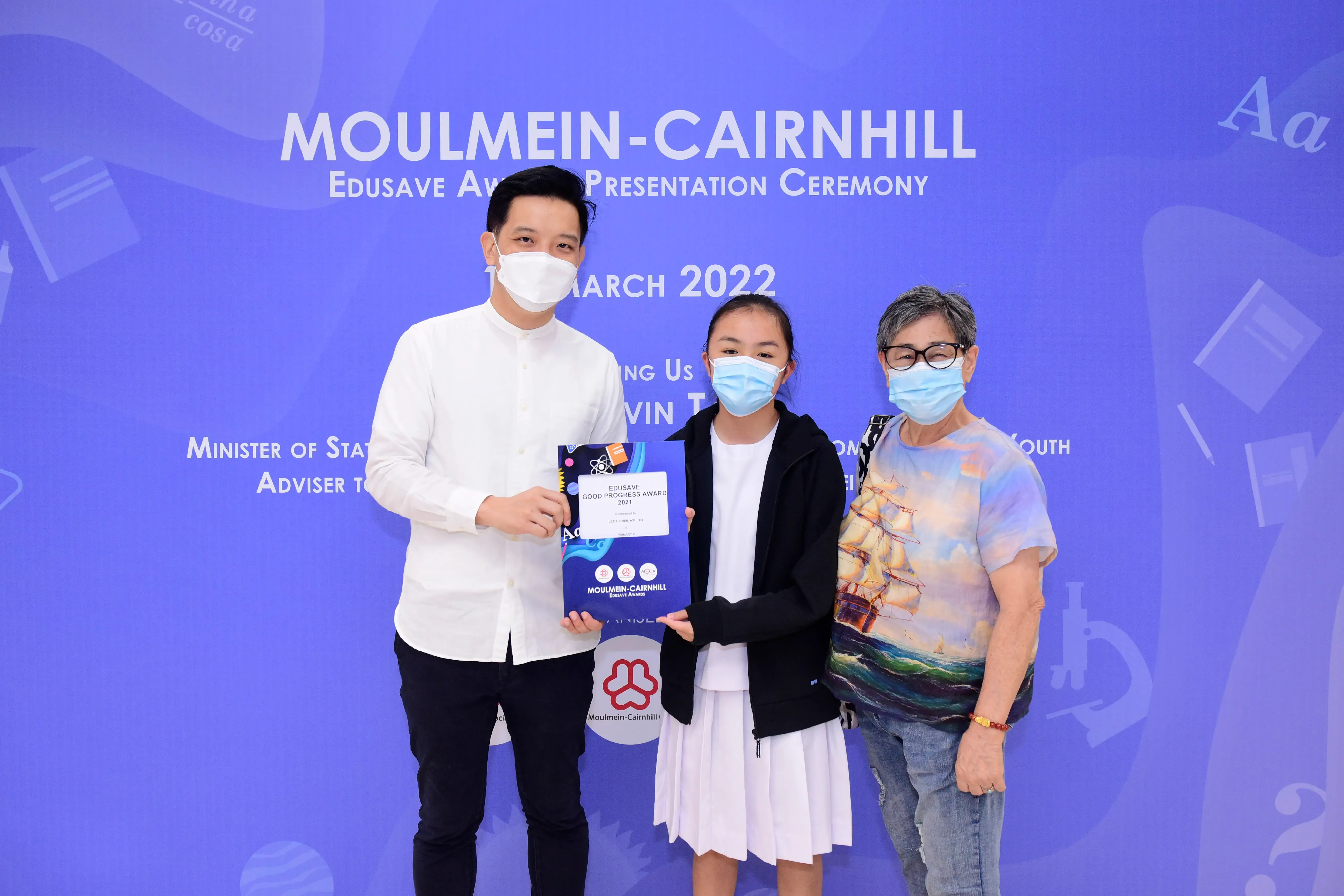 Three masked people pose at the Moulmein-Cairnhill Edusave Award Presentation Ceremony in March 2022.