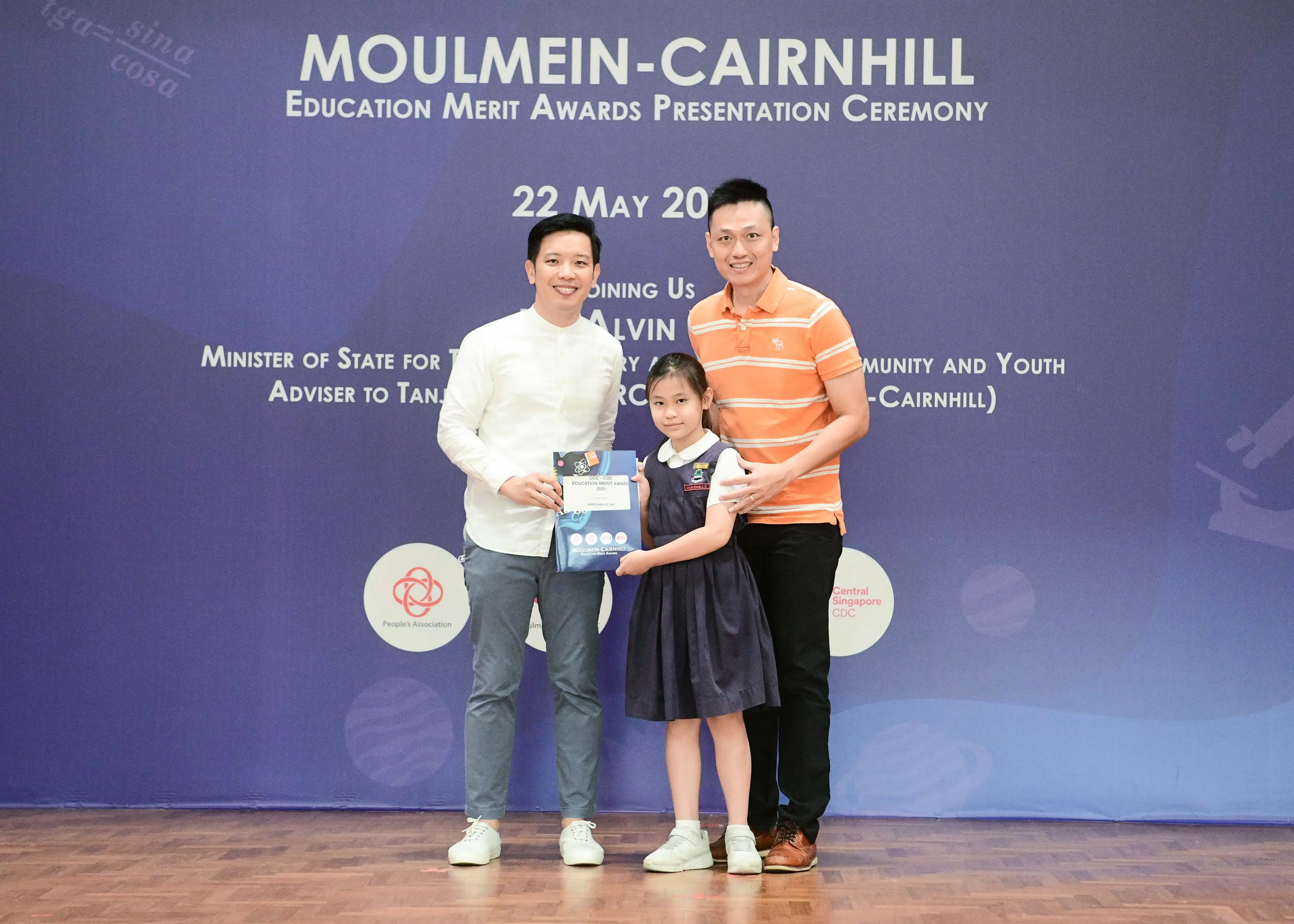 Two men and a young girl pose at the Moulmein-Cairnhill Education Merit Awards Presentation Ceremony.