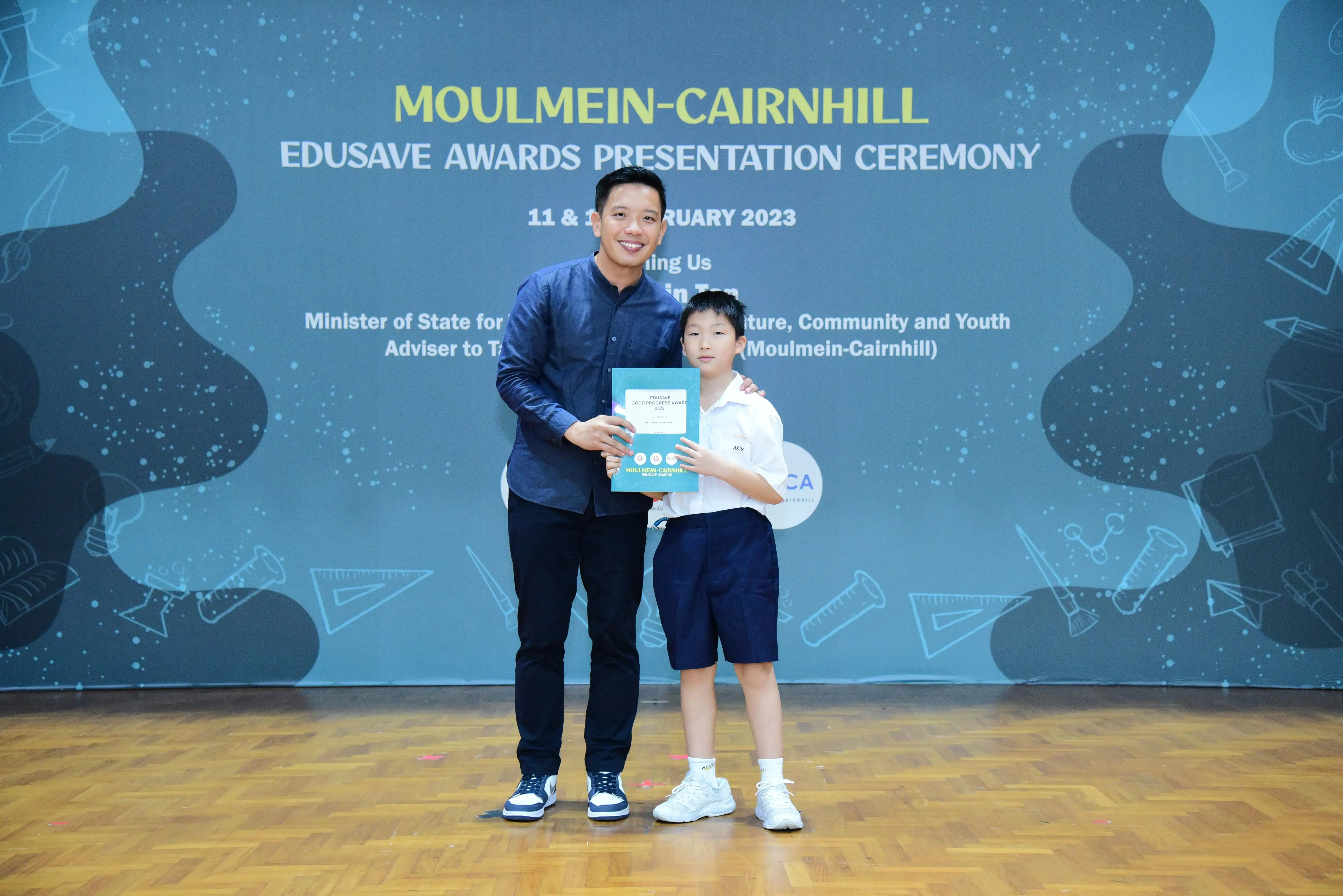 Adult and young student hold a certificate at Moulmein-Cairnhill Edusave Awards Presentation Ceremony 2023.