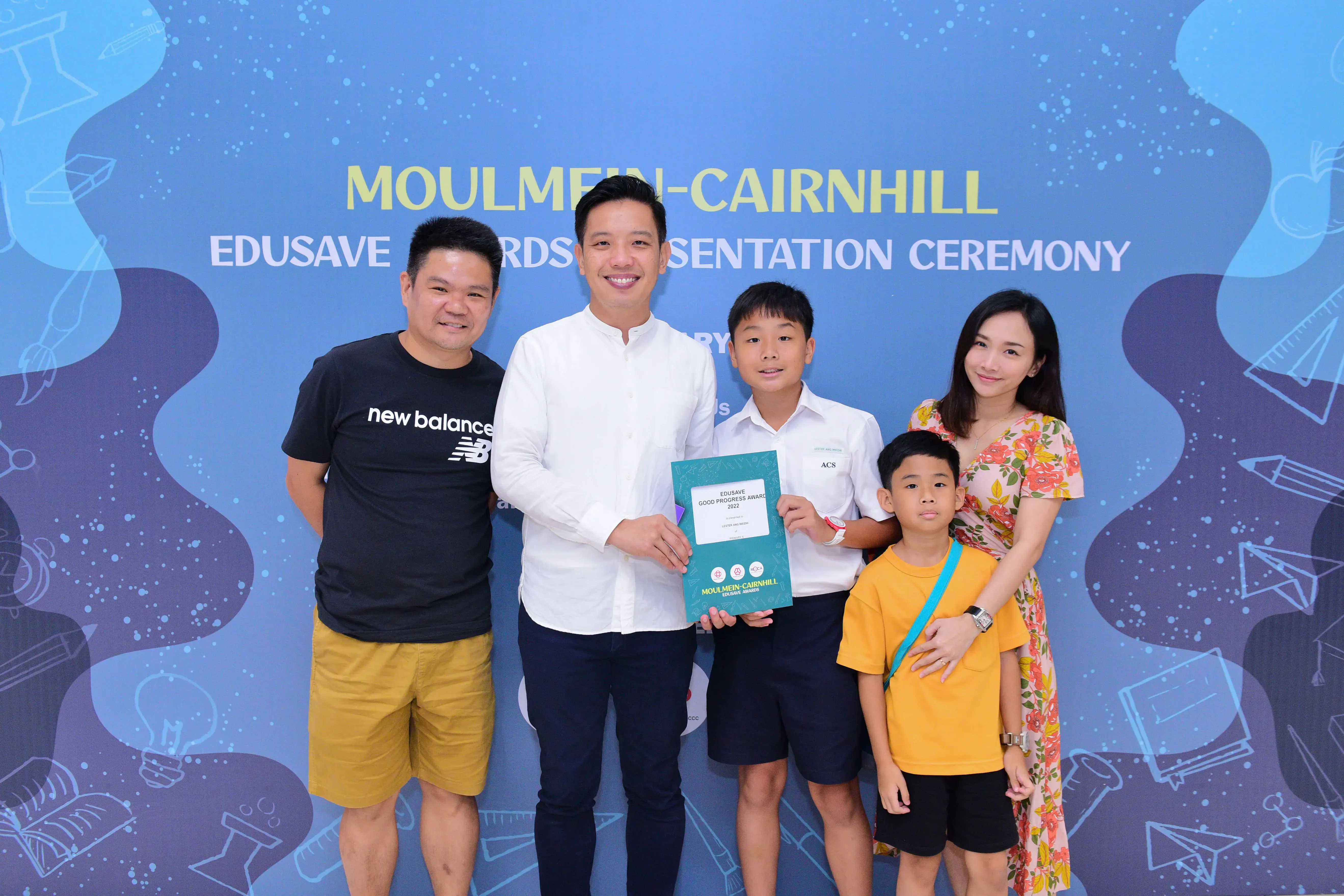 Five people pose at the Moulmein-Cairnhill Edusave Awards Presentation Ceremony, with a boy holding a teal award certificate.