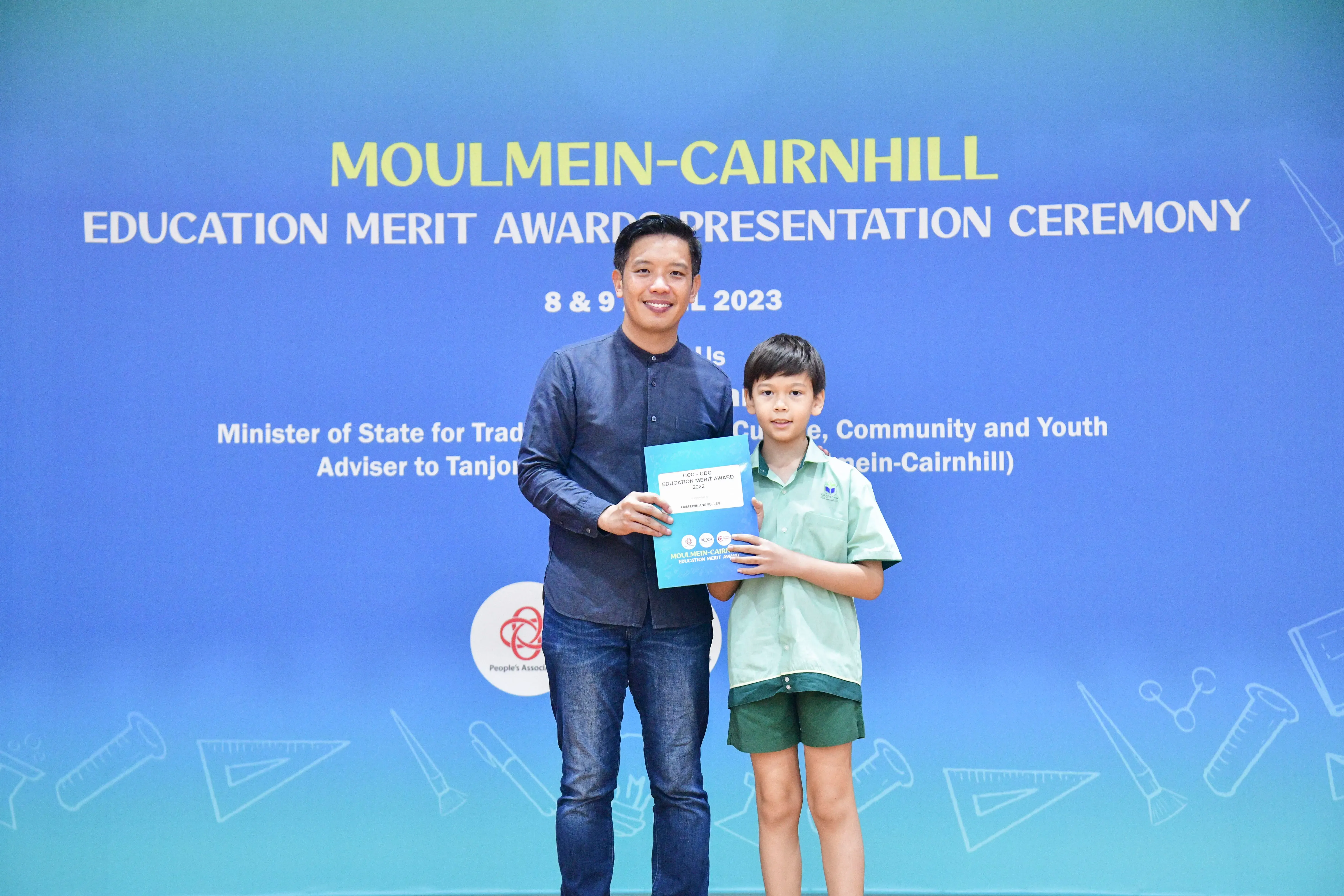 Man and young boy hold a certificate at the Moulmein-Cairnhill Education Merit Award Ceremony 2023.