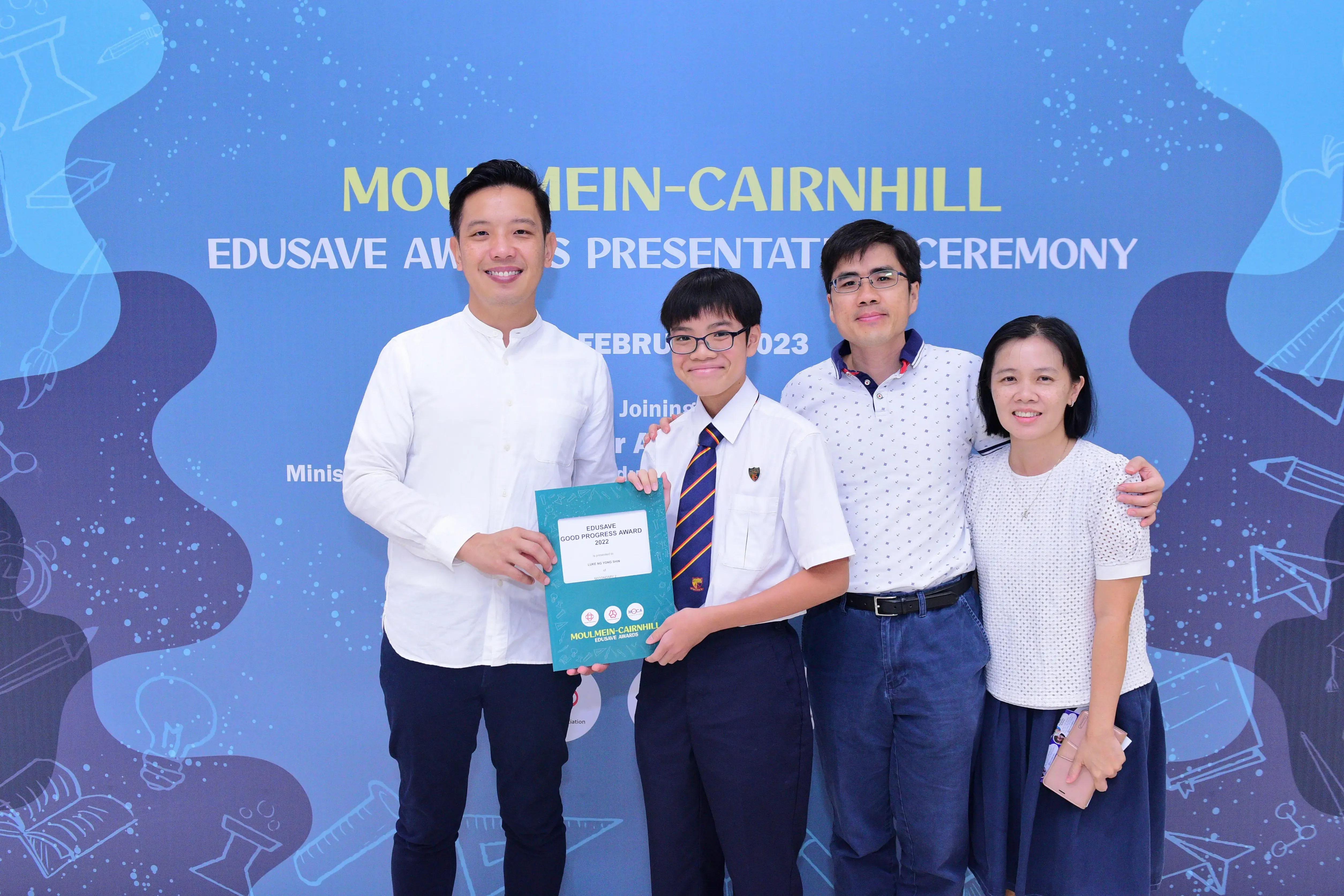 Four people pose at the Moulmein-Cairnhill Edusave Awards Ceremony 2023, with a student holding a certificate.