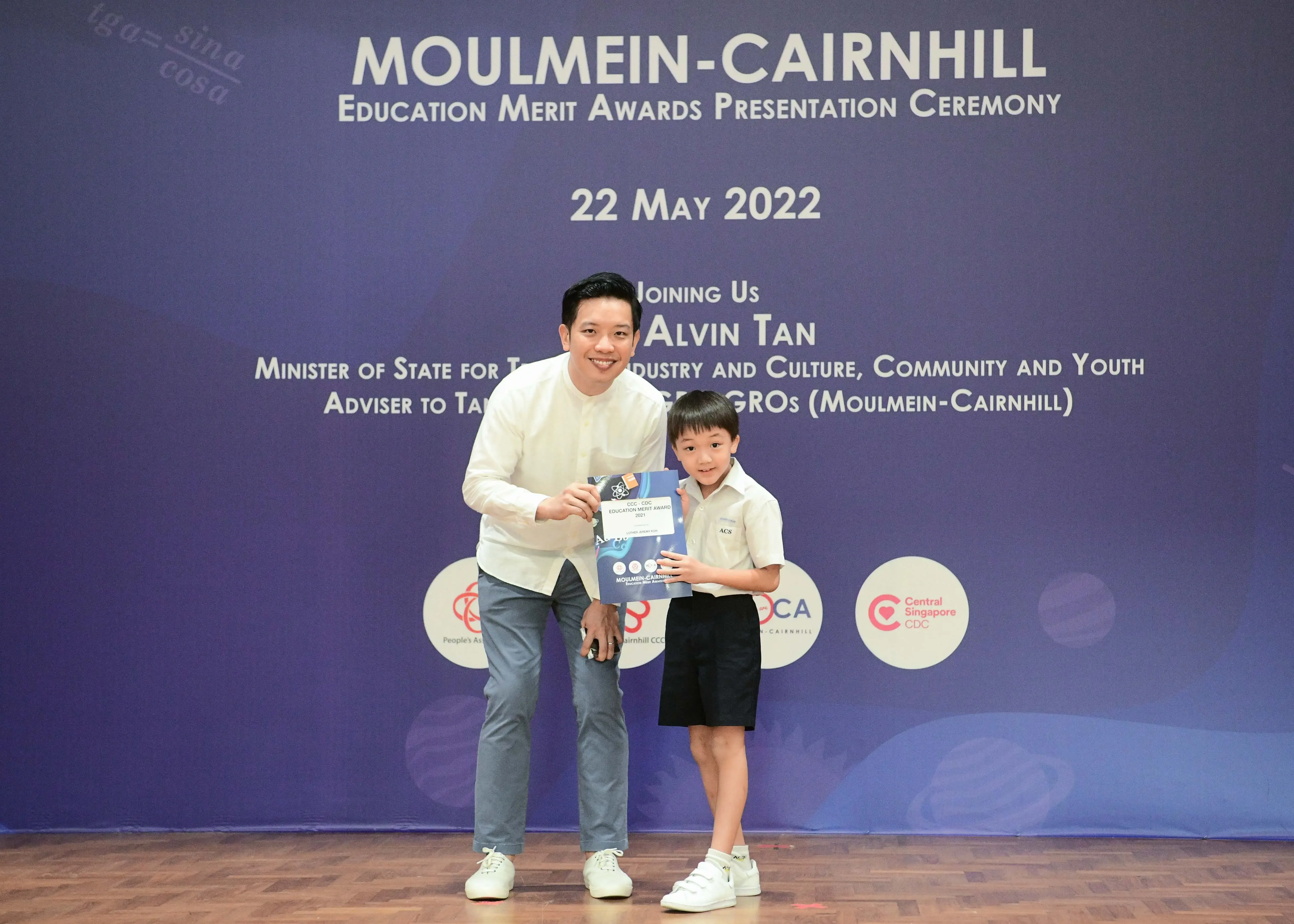 A man and a young boy hold a certificate together at the Moulmein-Cairnhill Education Merit Awards on 22 May 2022.
