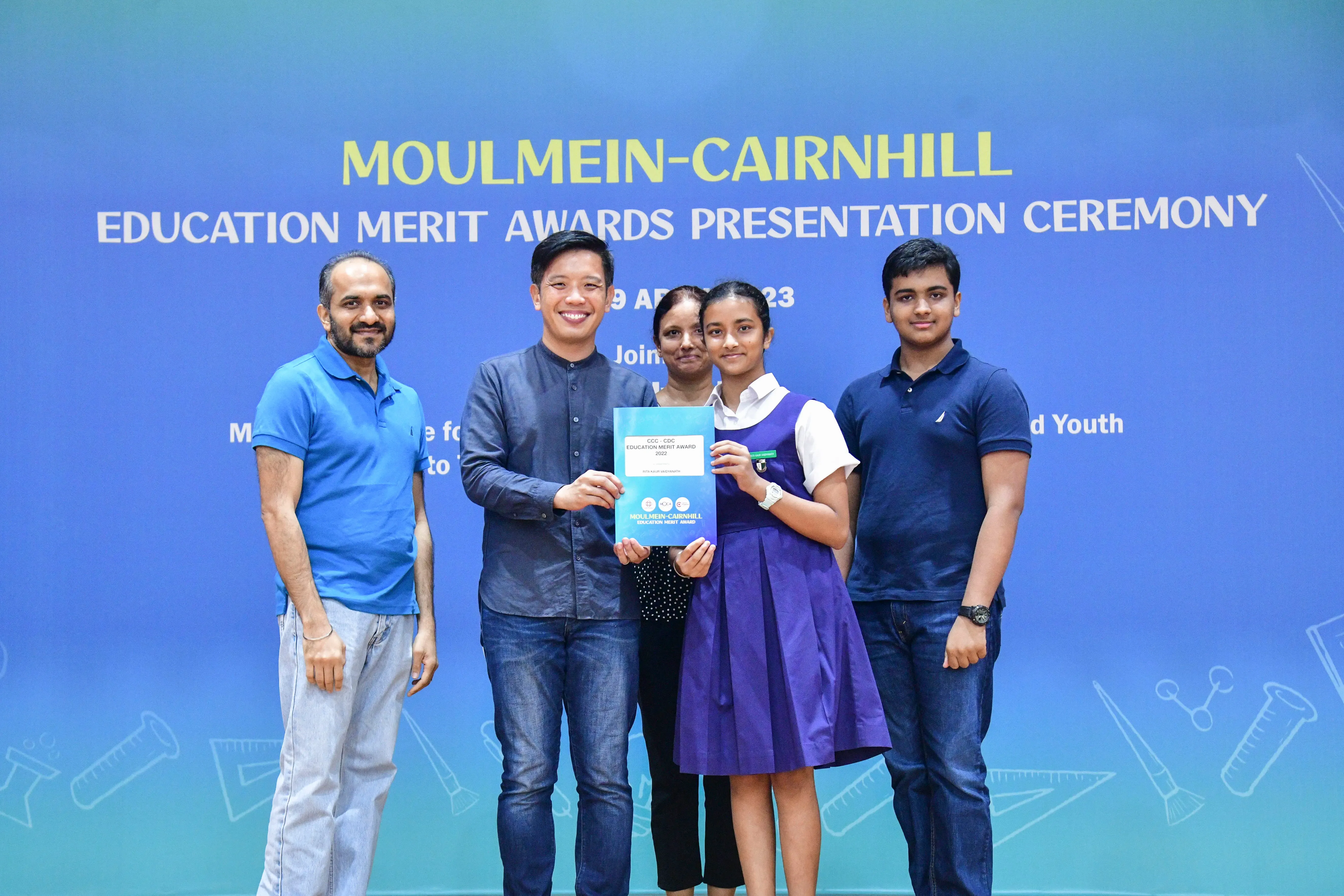 Five people pose at the Moulmein-Cairnhill Education Merit Awards Presentation Ceremony, holding an award certificate.