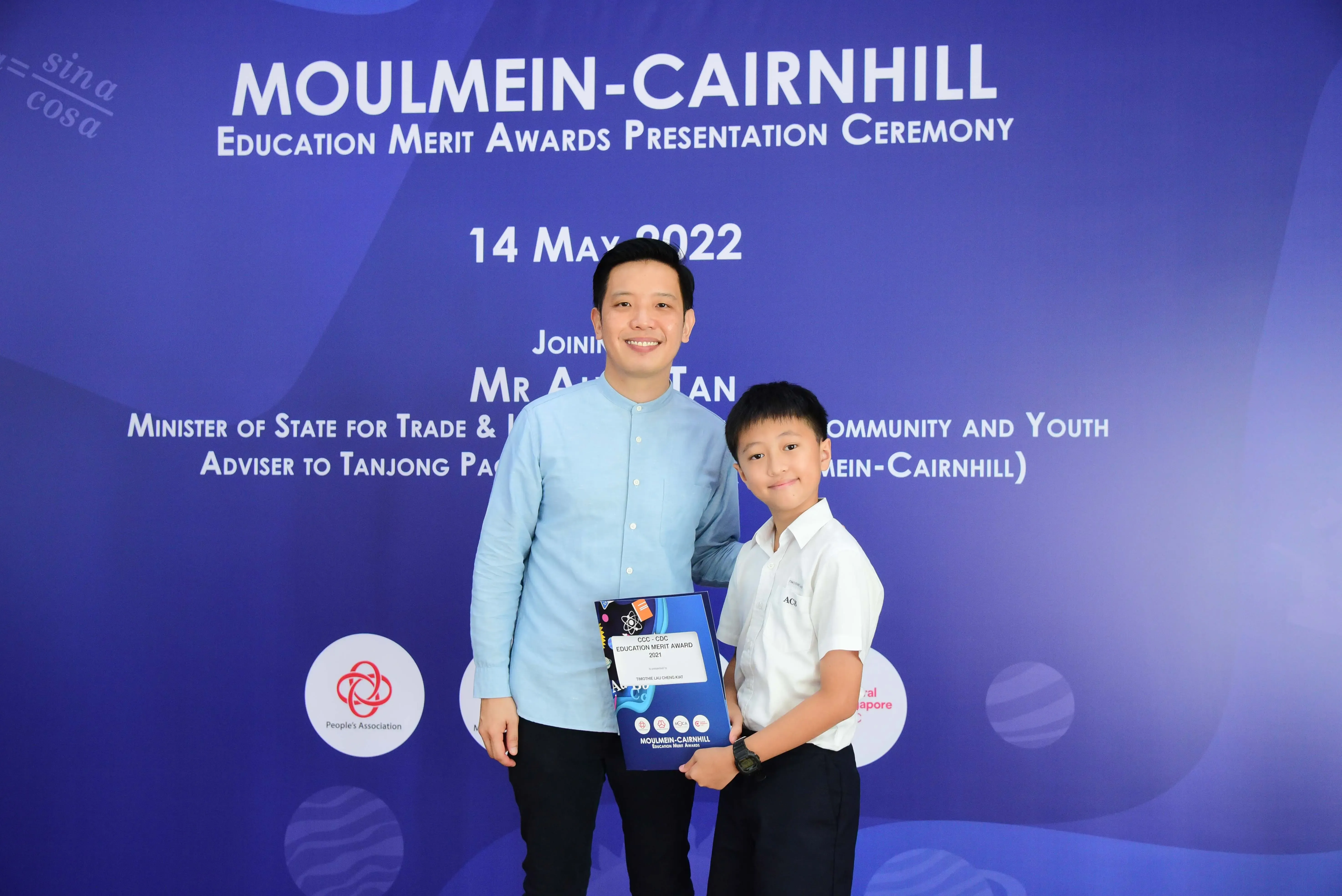 A man and a young boy hold an award certificate at the Moulmein-Cairnhill Education Merit Awards ceremony on 14 May 2022.
