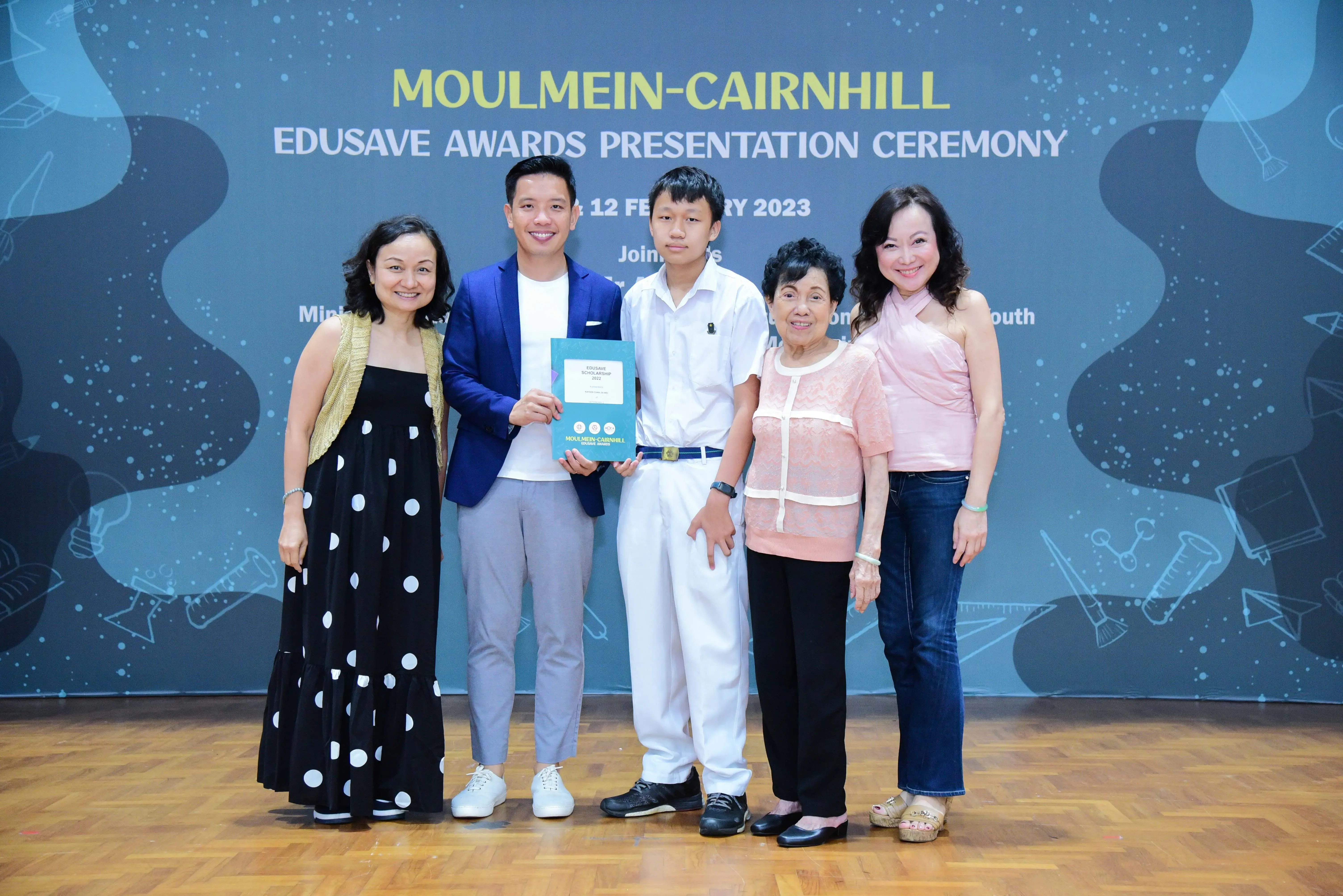Five people pose smiling at the Moulmein-Cairnhill Edusave Awards Presentation Ceremony on 12 February 2023.