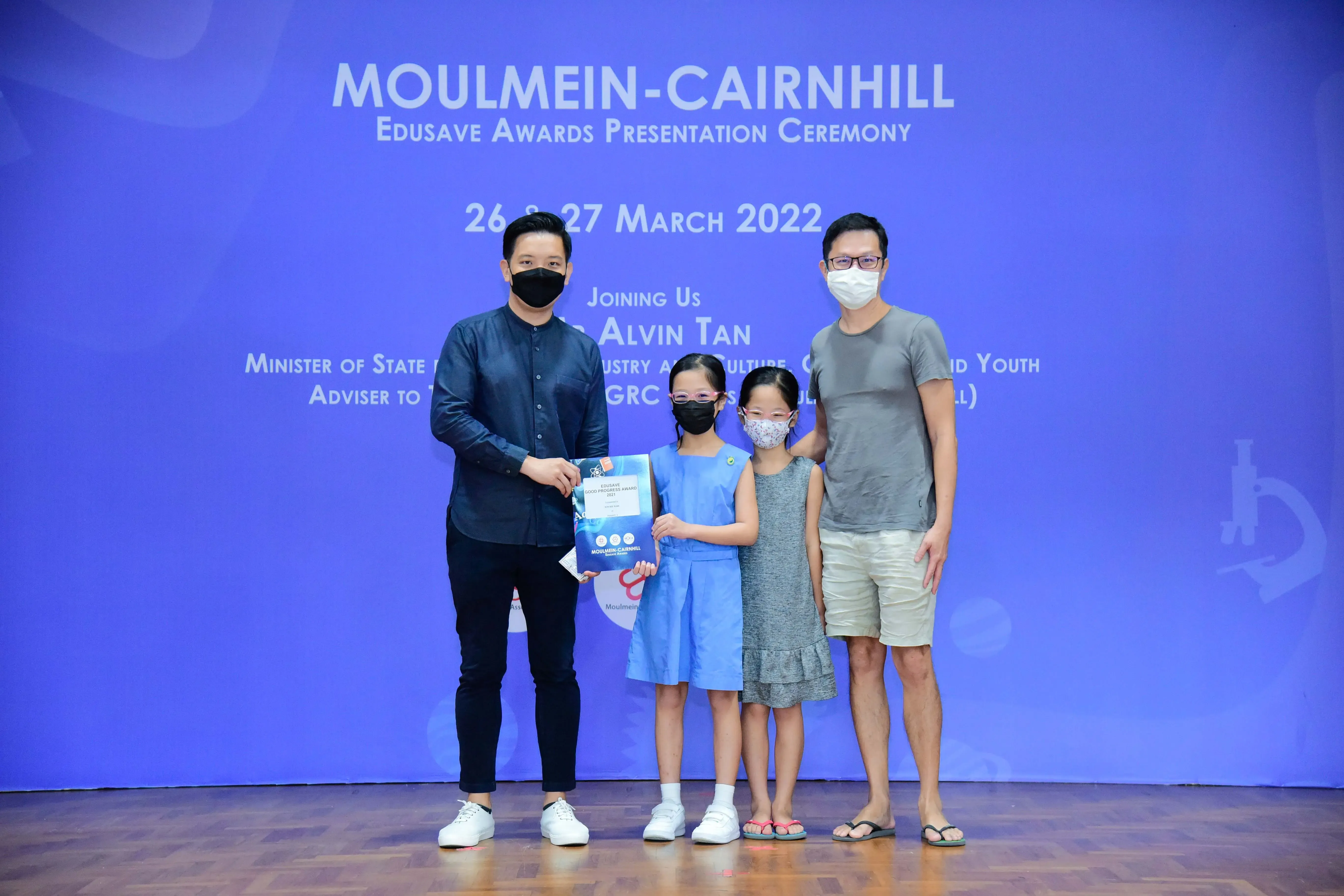 Two masked men and two young girls pose at the Moulmein-Cairnhill Edusave Awards Ceremony on 26-27 March 2022.