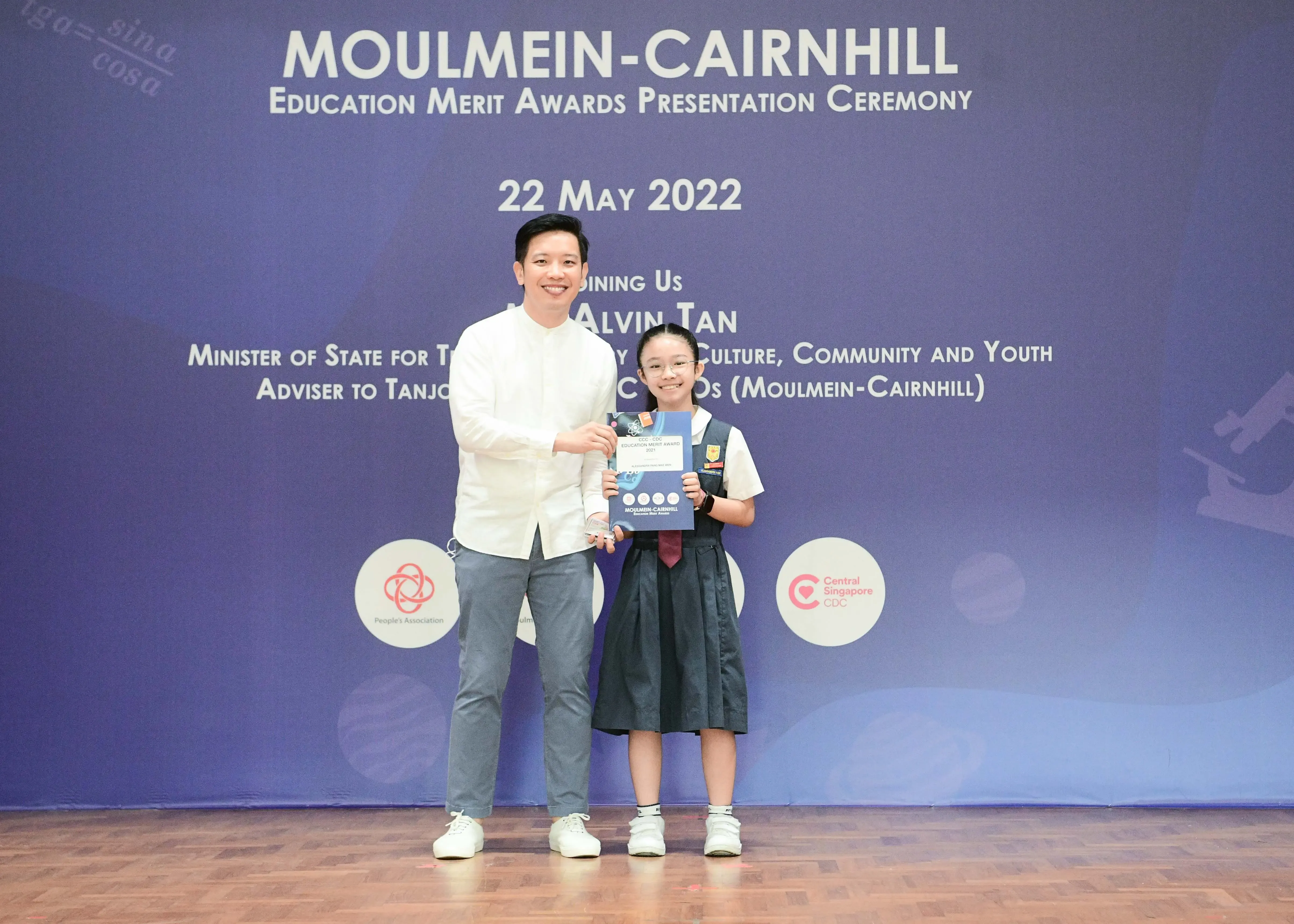 A man and a young girl in school uniform pose with an award at the Moulmein-Cairnhill Education Merit Awards 2022.