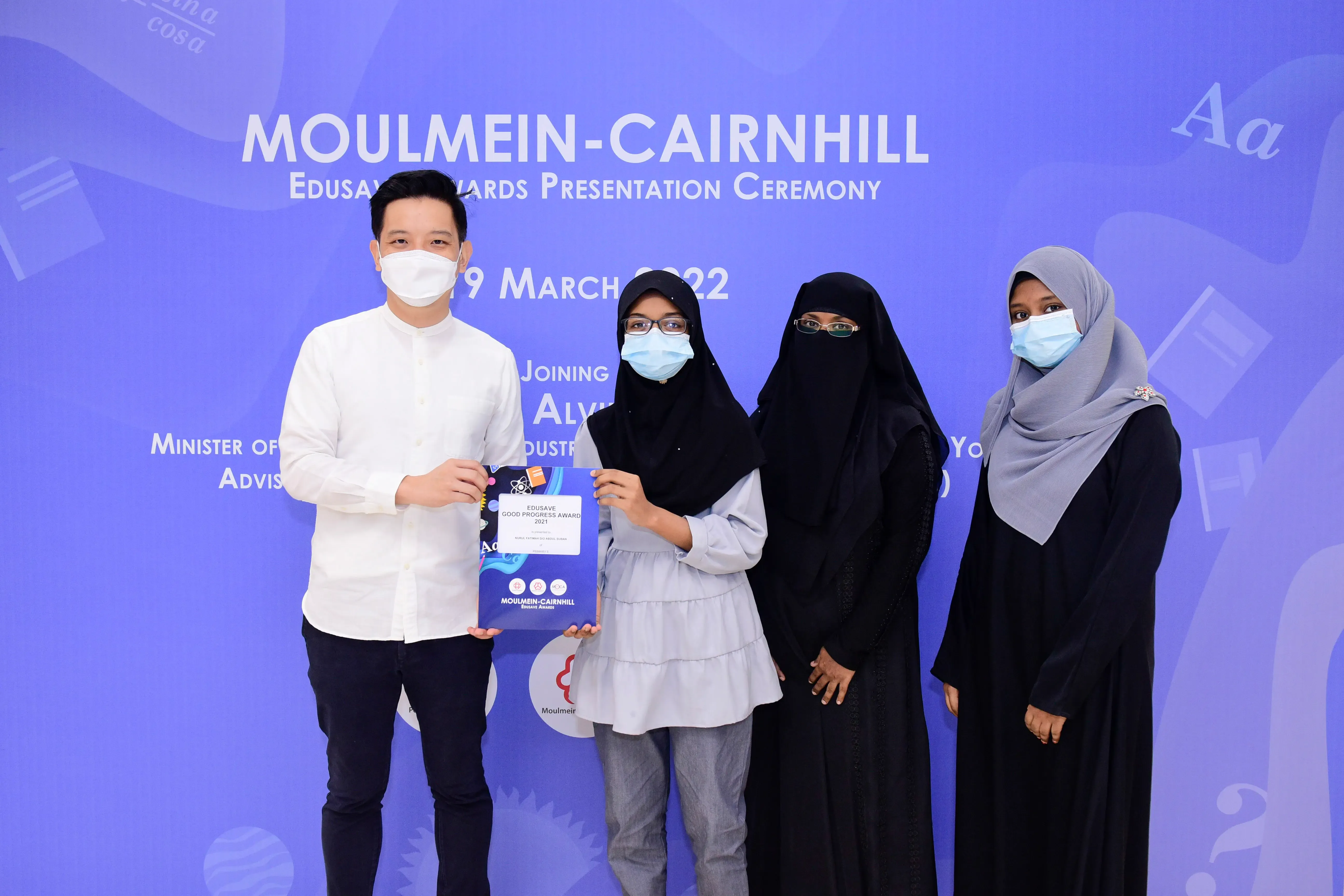 Four masked people pose at the Moulmein-Cairnhill Edusave Awards Presentation Ceremony on 19 March 2022.
