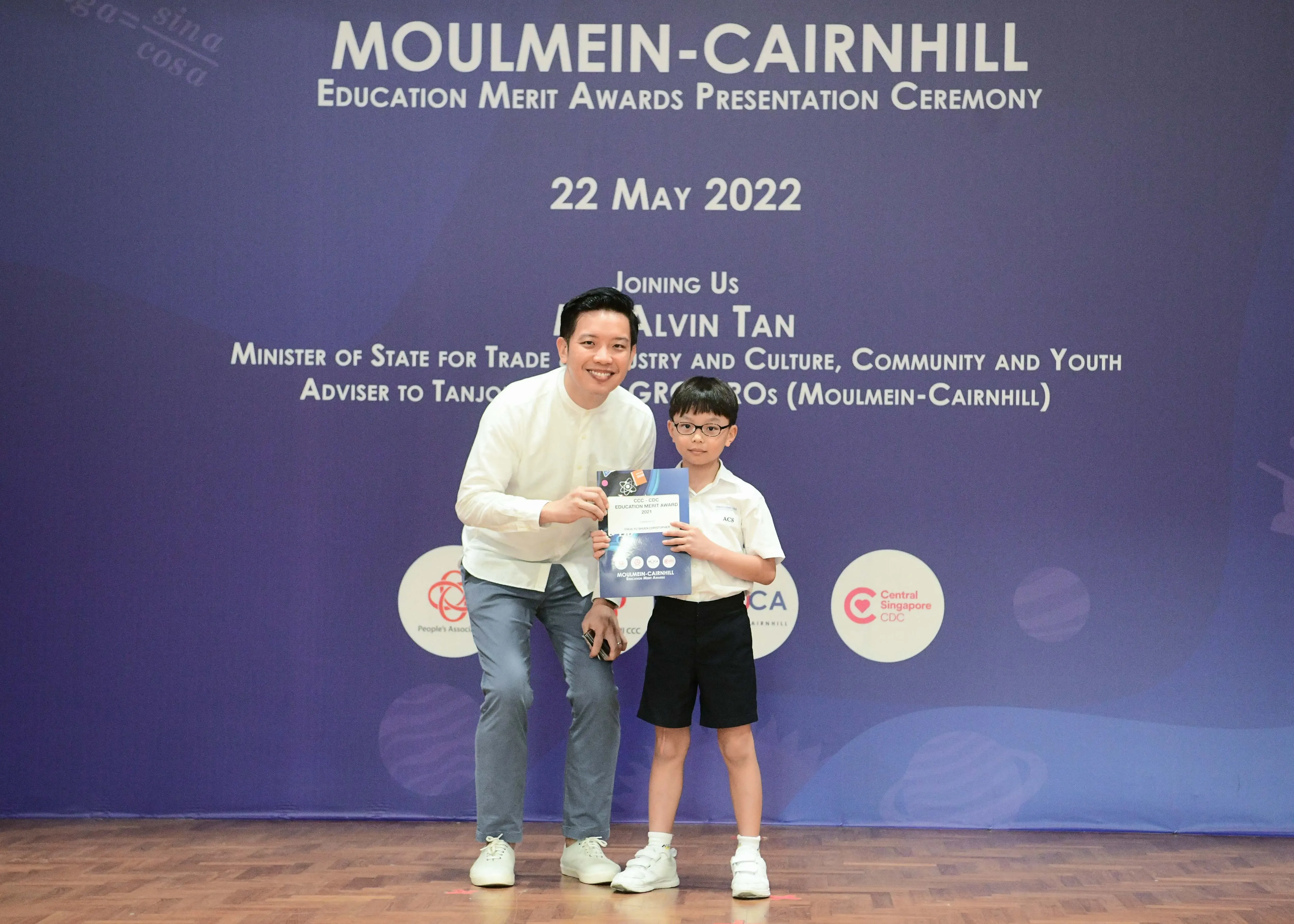 A man and a young boy hold an award certificate at the Moulmein-Cairnhill Education Merit Awards ceremony on 22 May 2022.