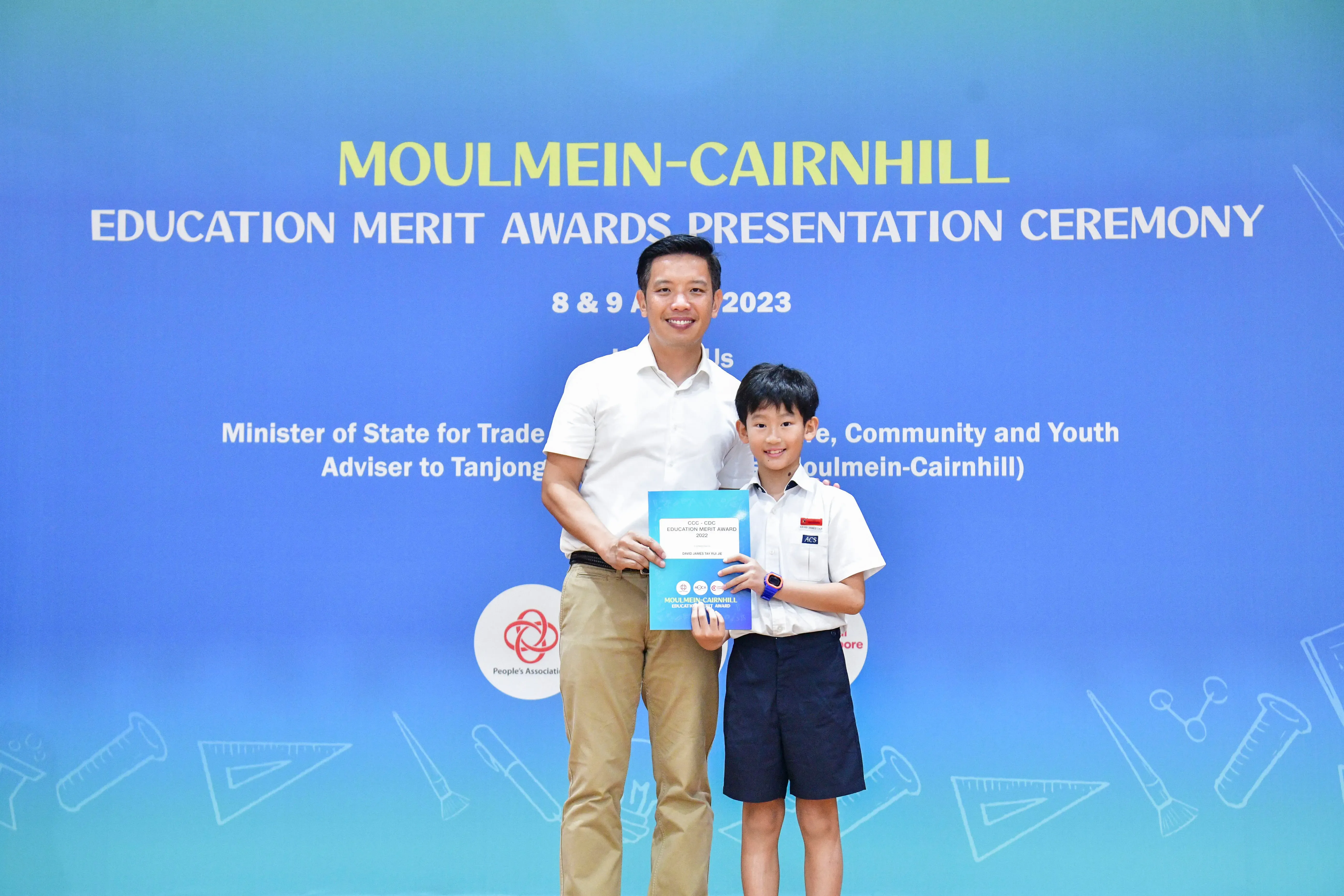 A man and a young boy pose together holding an award certificate at the Moulmein-Cairnhill Education Merit Awards 2023.