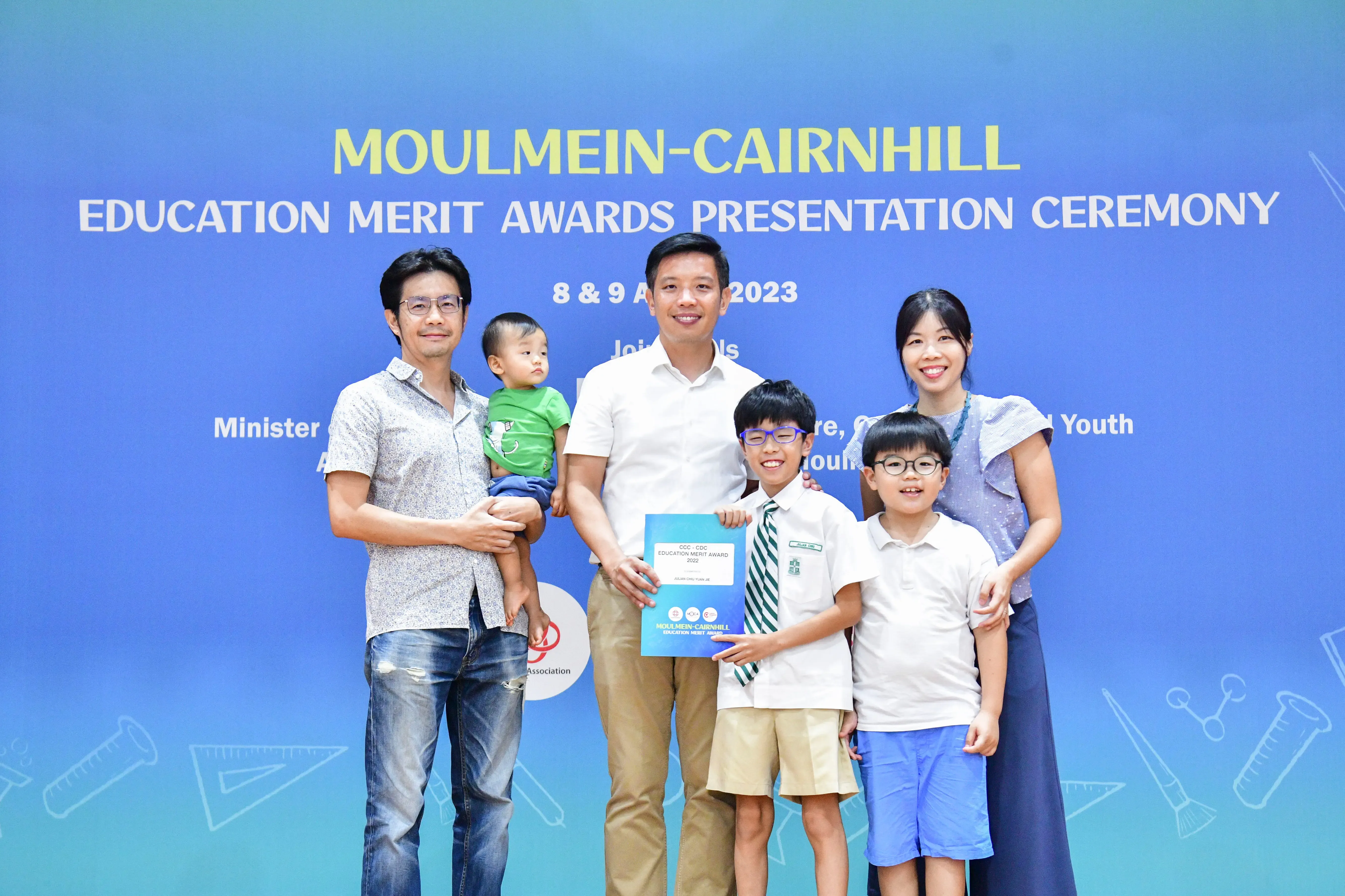 A family of five poses with an award certificate at the Moulmein-Cairnhill Education Merit Awards Ceremony 2023.