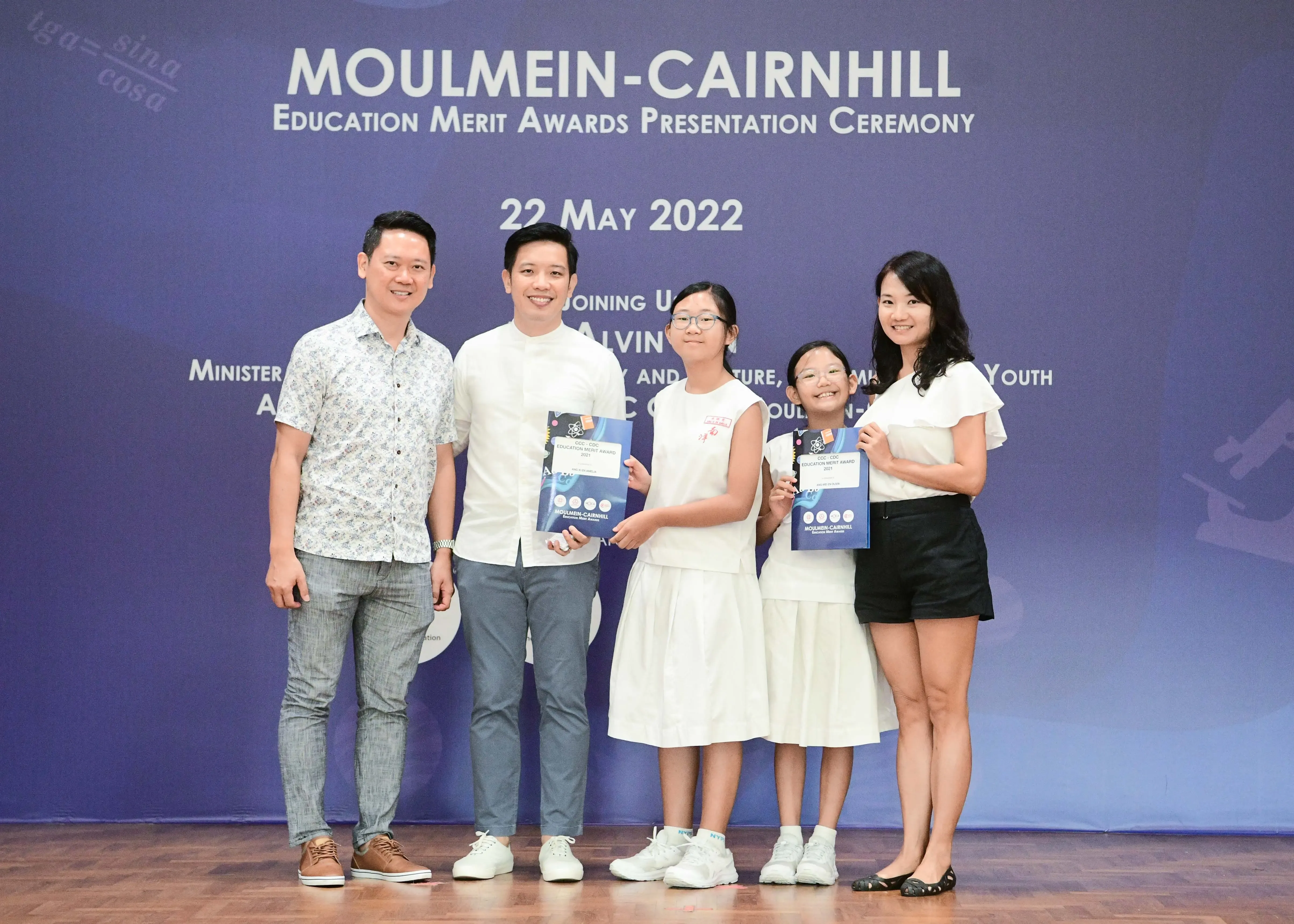 Five people pose on stage at the Moulmein-Cairnhill Education Merit Awards Presentation Ceremony on 22 May 2022.