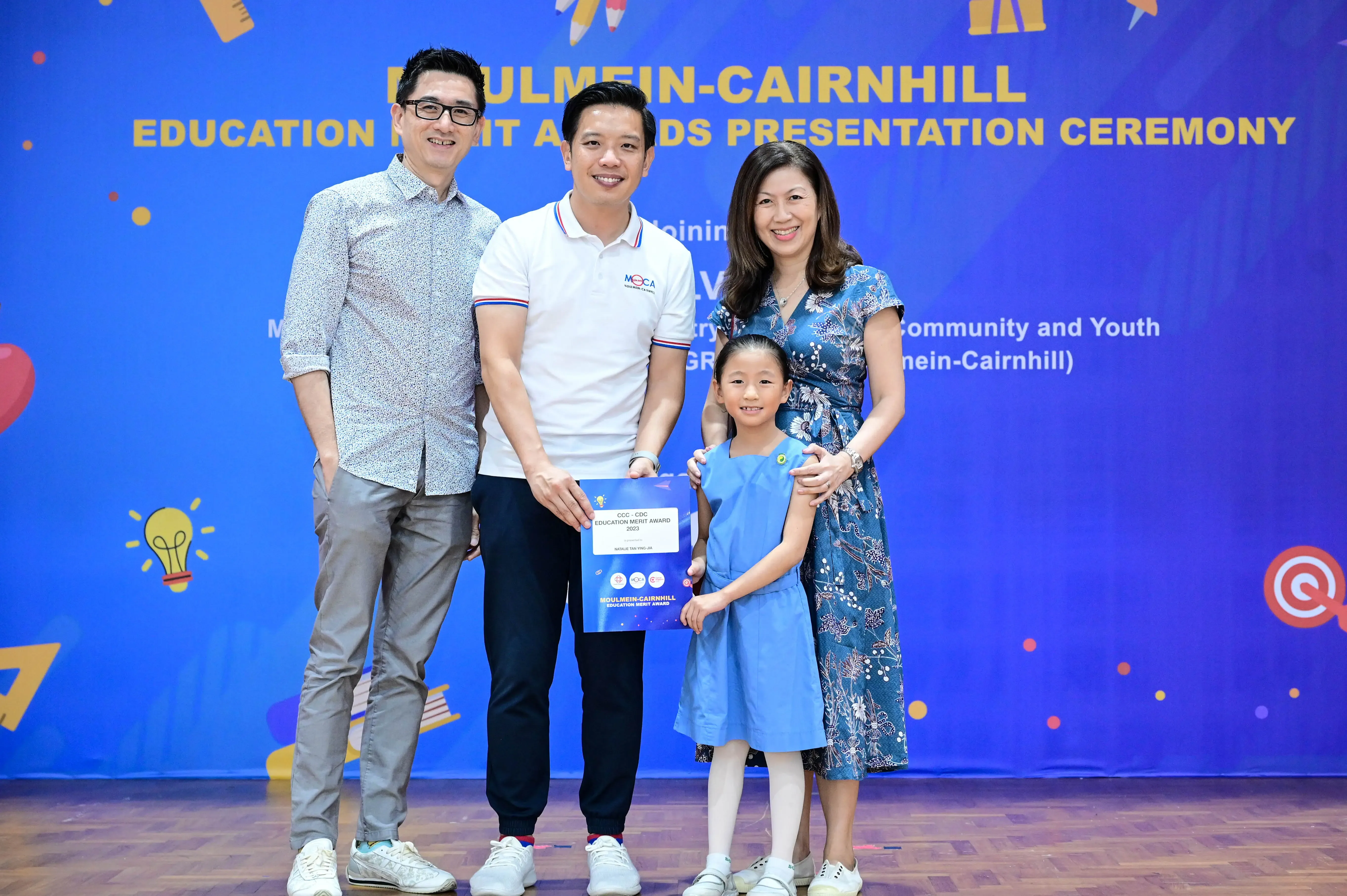 Three adults and a young girl pose with an award certificate at the Moulmein-Cairnhill Education Merit Awards Presentation Ceremony.