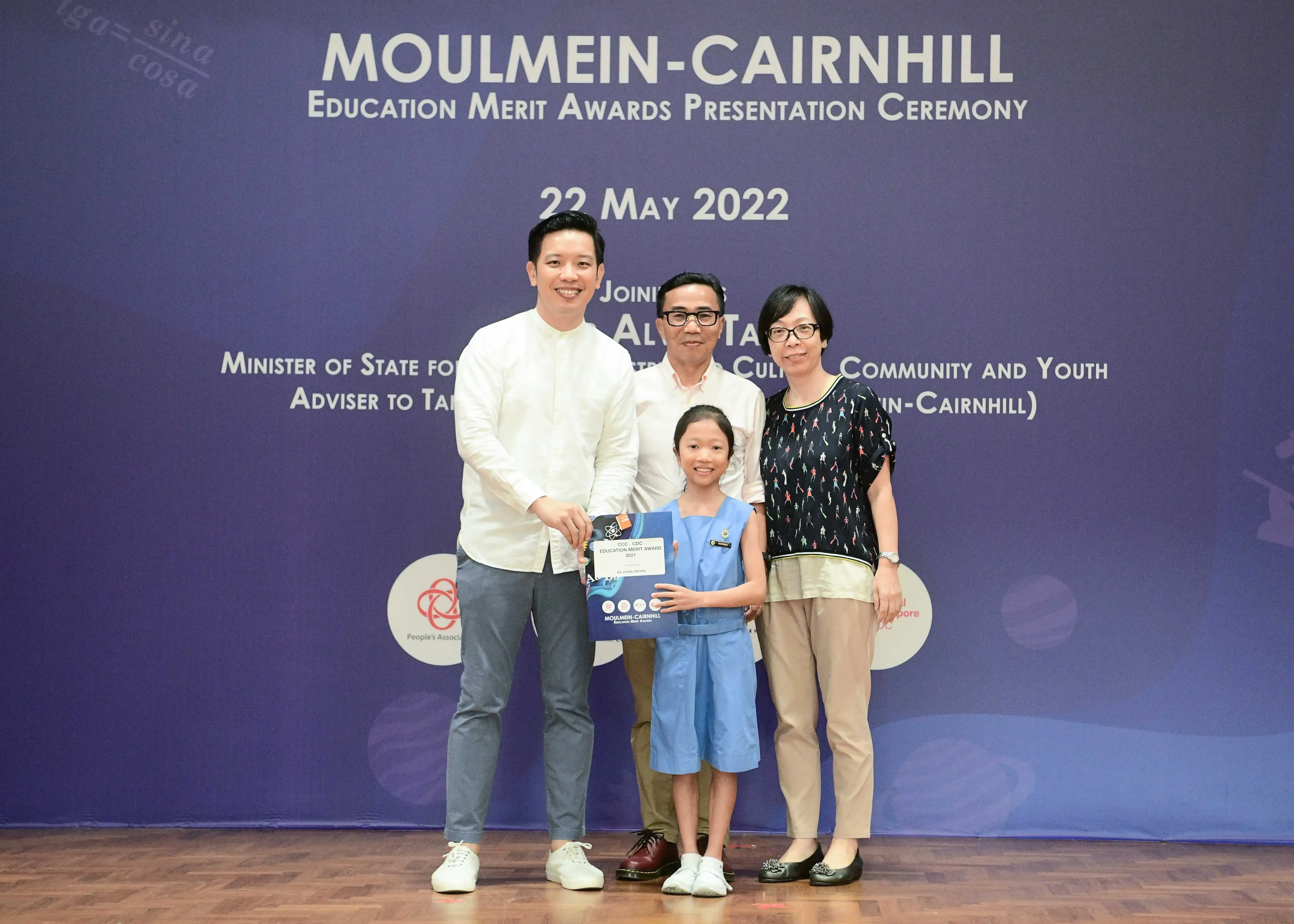 Three adults and a young girl holding a certificate pose at the Moulmein-Cairnhill Education Merit Awards ceremony on 22 May 2022.