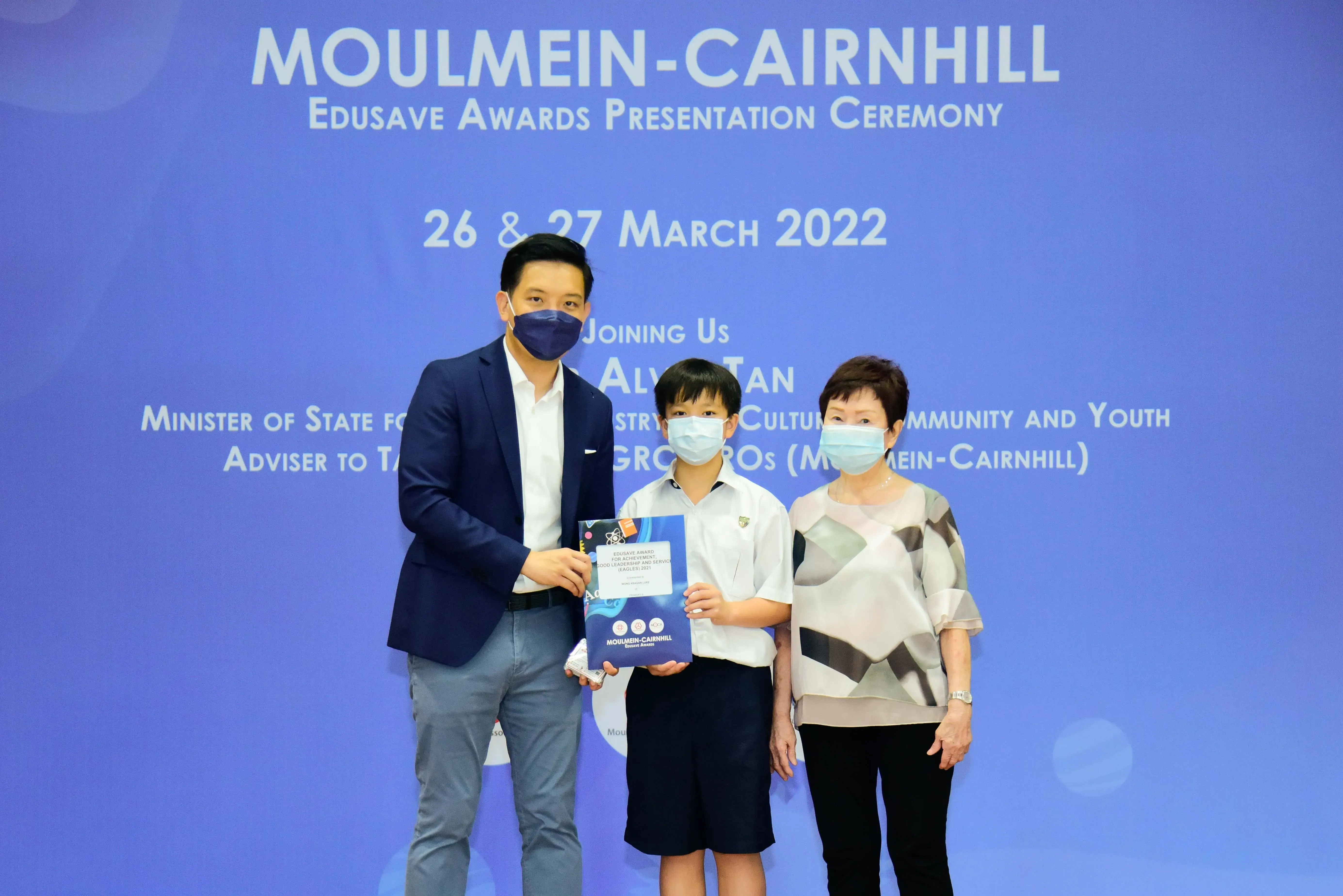 Three masked people pose at the Moulmein-Cairnhill Edusave Awards Presentation Ceremony on 26-27 March 2022.