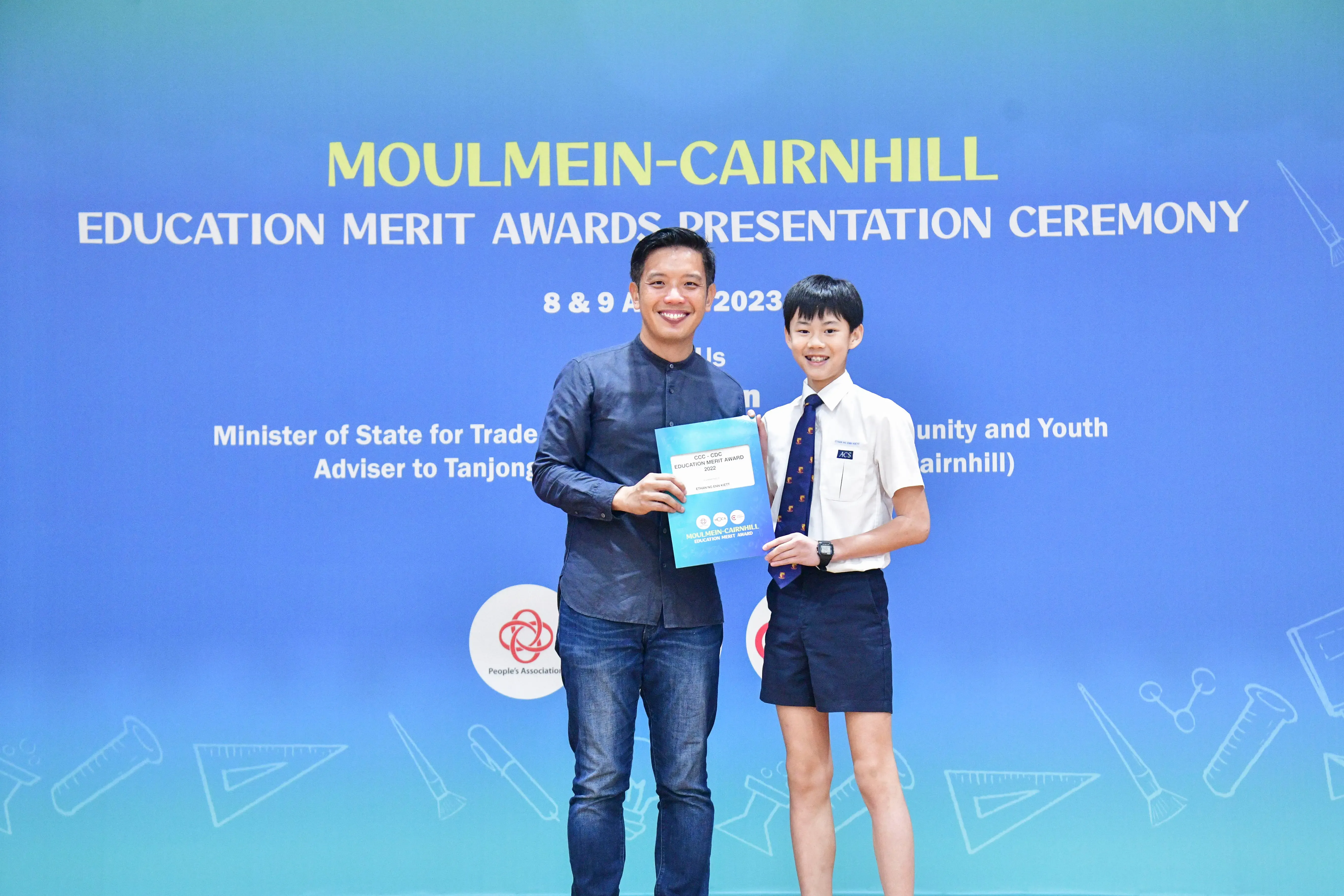 An adult and a uniformed student pose together holding an award at the Moulmein-Cairnhill Education Merit Awards 2023.