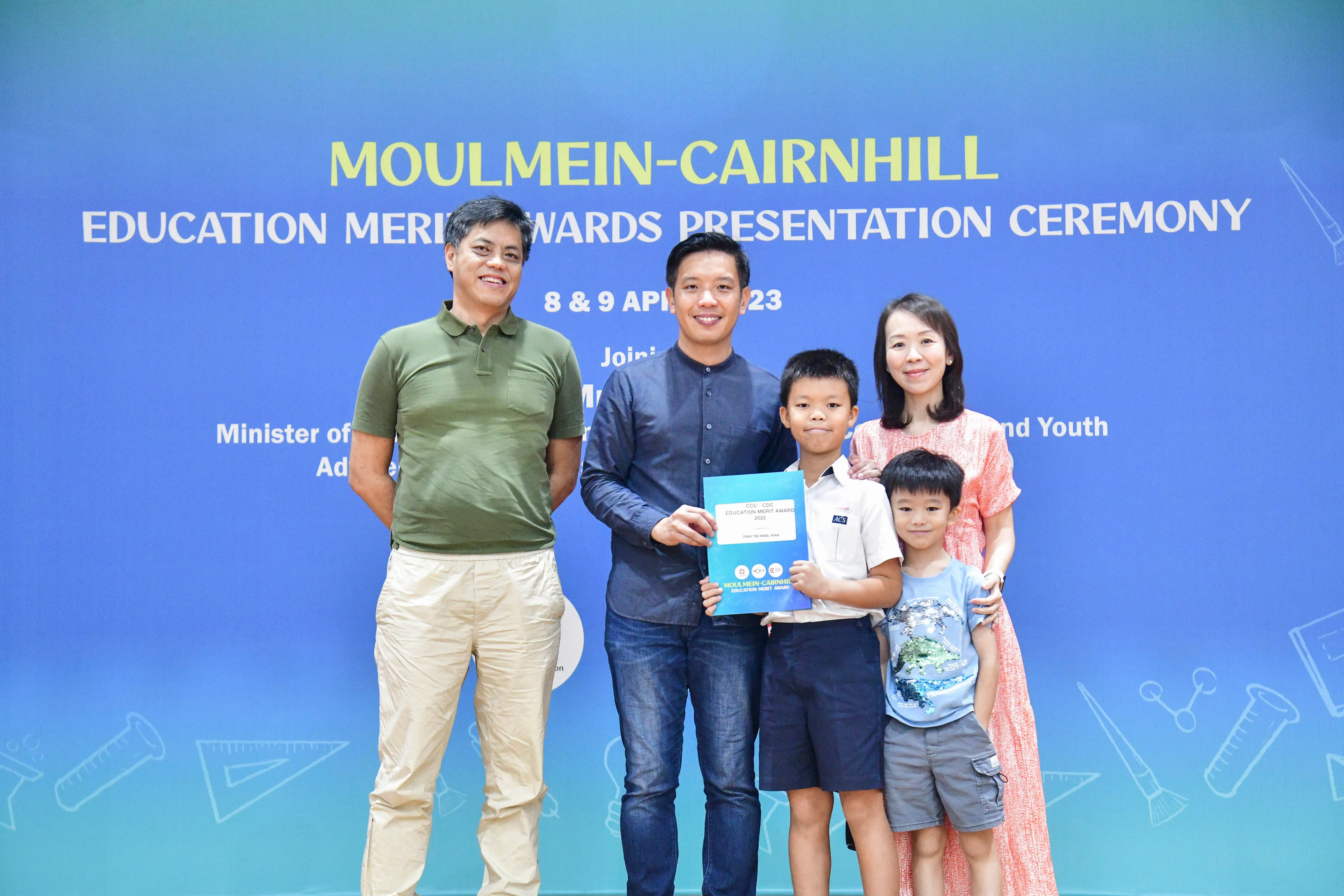 Five people pose with a blue award folder at the Moulmein-Cairnhill Education Merit Awards Ceremony, April 2023.