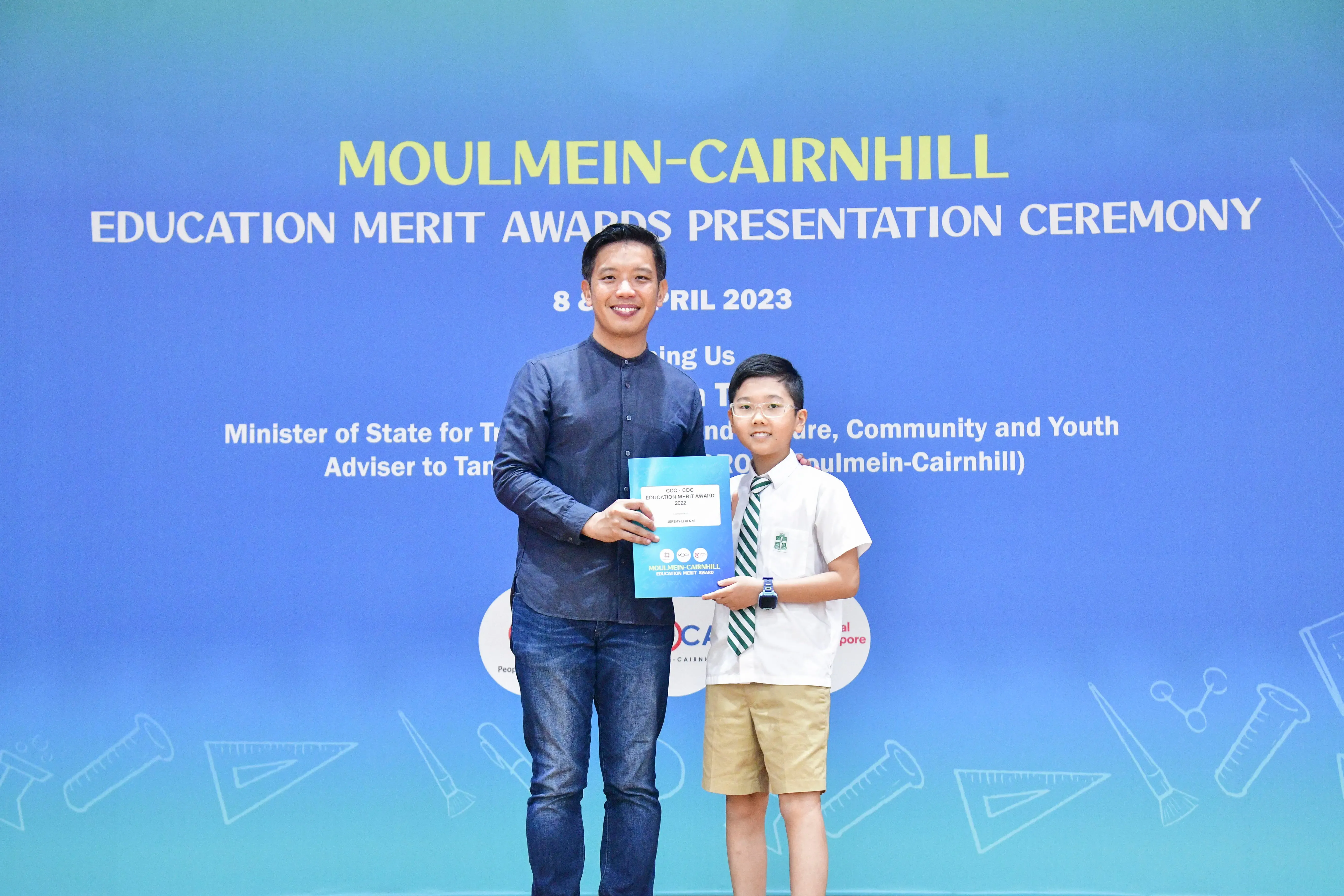 A man and a young boy in school uniform hold an award certificate at the Moulmein-Cairnhill Education Merit Awards 2023.