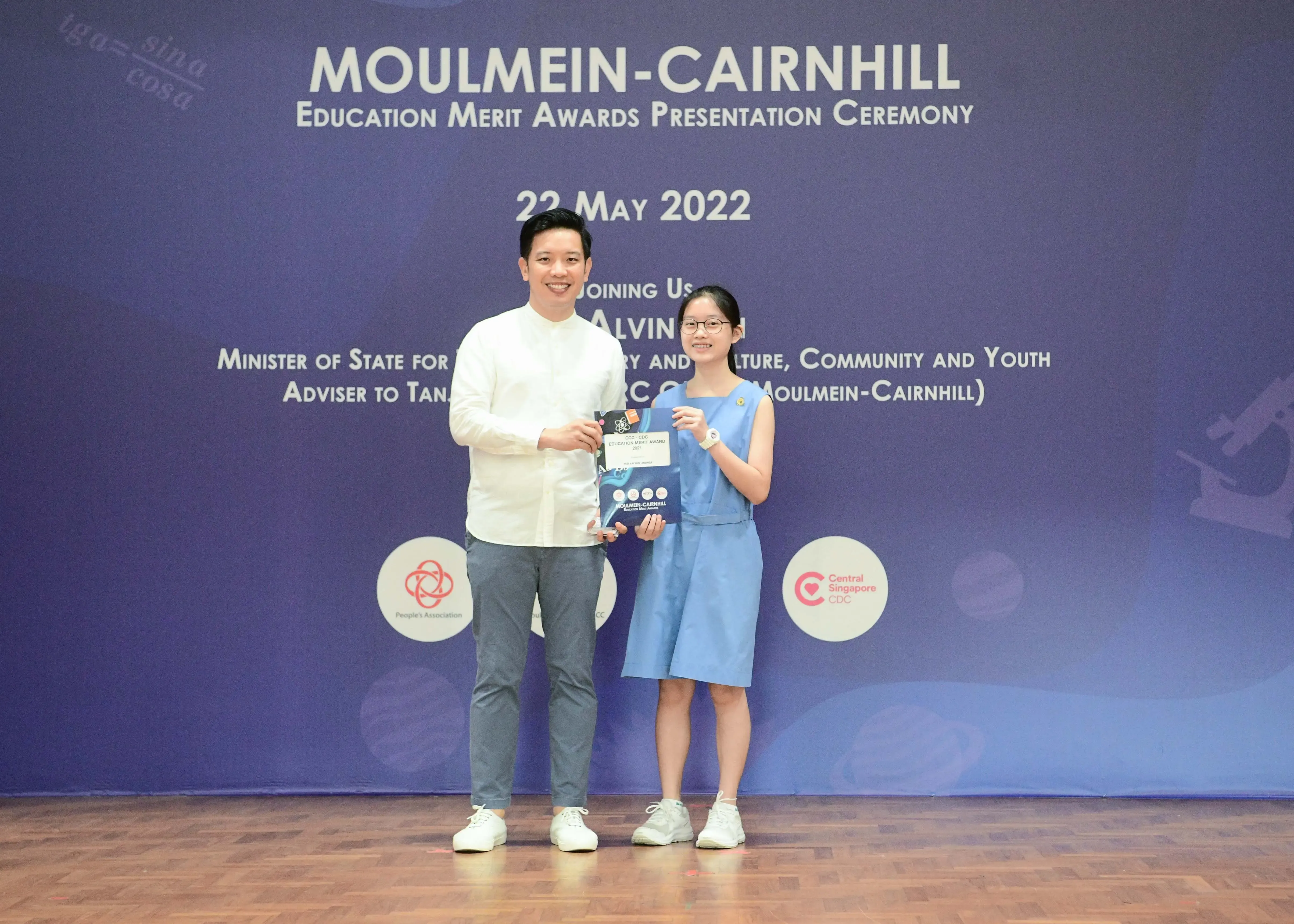 A man and a young girl hold an award together at the Moulmein-Cairnhill Education Merit Awards Ceremony on 22 May 2022.