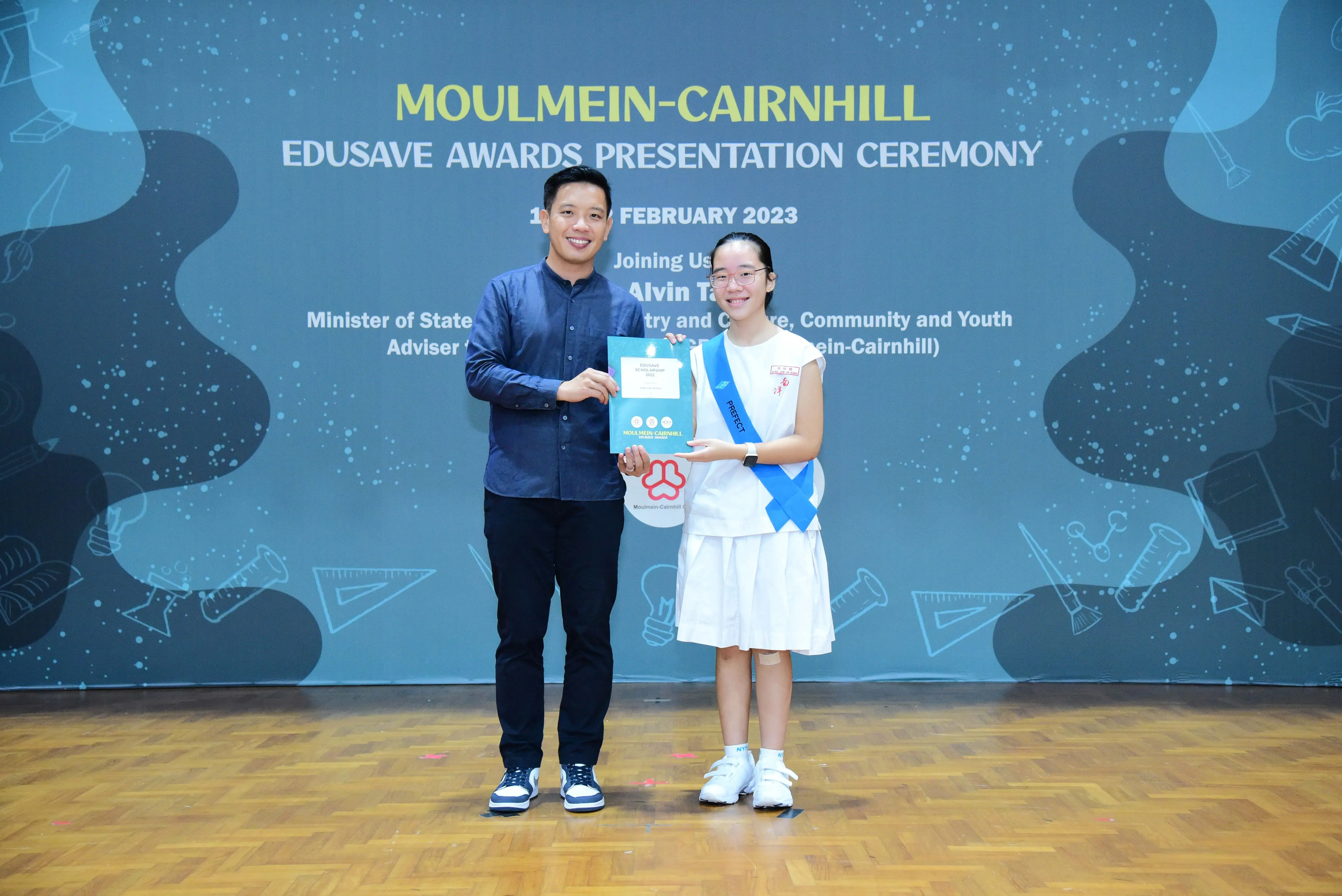 A man and a young girl hold a certificate at the Moulmein-Cairnhill Edusave Awards Presentation Ceremony 2023.