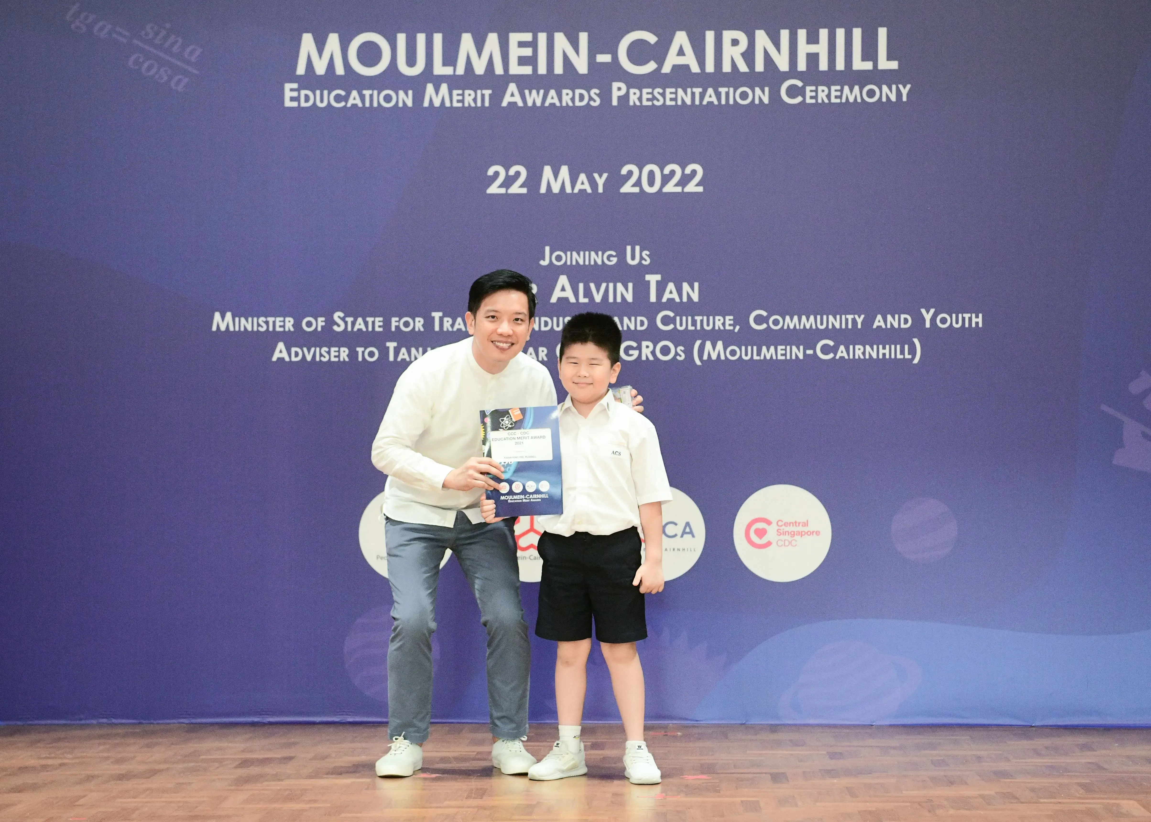 Man and young boy pose holding a certificate at Moulmein-Cairnhill Education Merit Awards on 22 May 2022.
